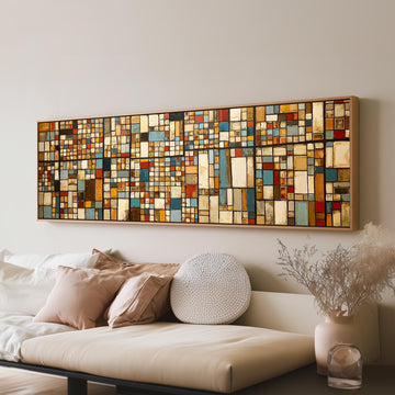 Earth tone mosaic grid in blue and ochre long horizontal canvas print above a sofa in a living room