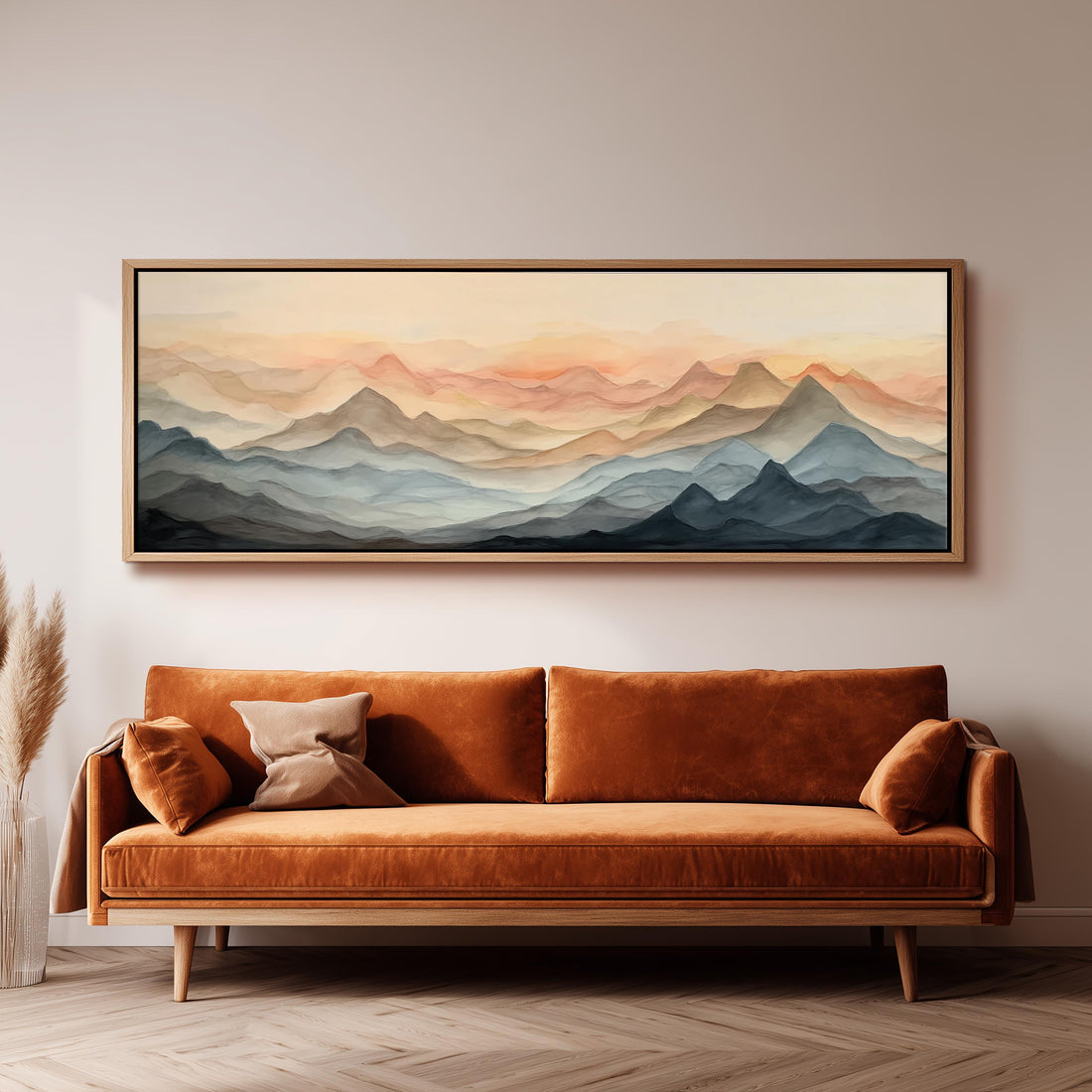 a large, framed painting of a mountain landscape hanging on a wall above a brown sofa with orange cushions.
