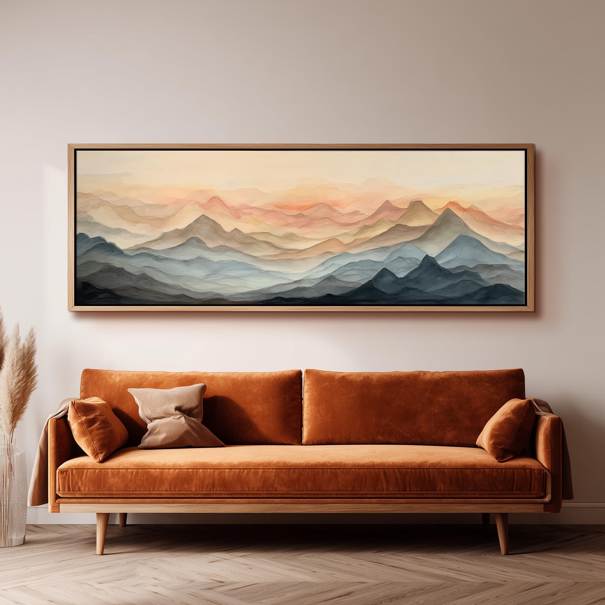 a large, framed painting of a mountain landscape hanging on a wall above a brown sofa with orange cushions.