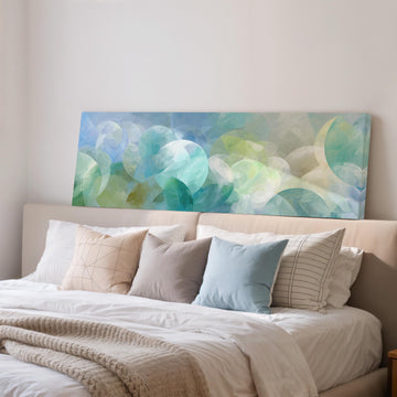 a large abstract painting hanging on a wall above a bed with white bedding and various pillows.