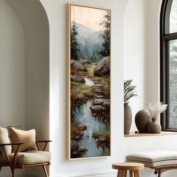 a large painting of a serene landscape with a stream, framed on a wall and hanging in a room with a seating area and decorative elements.