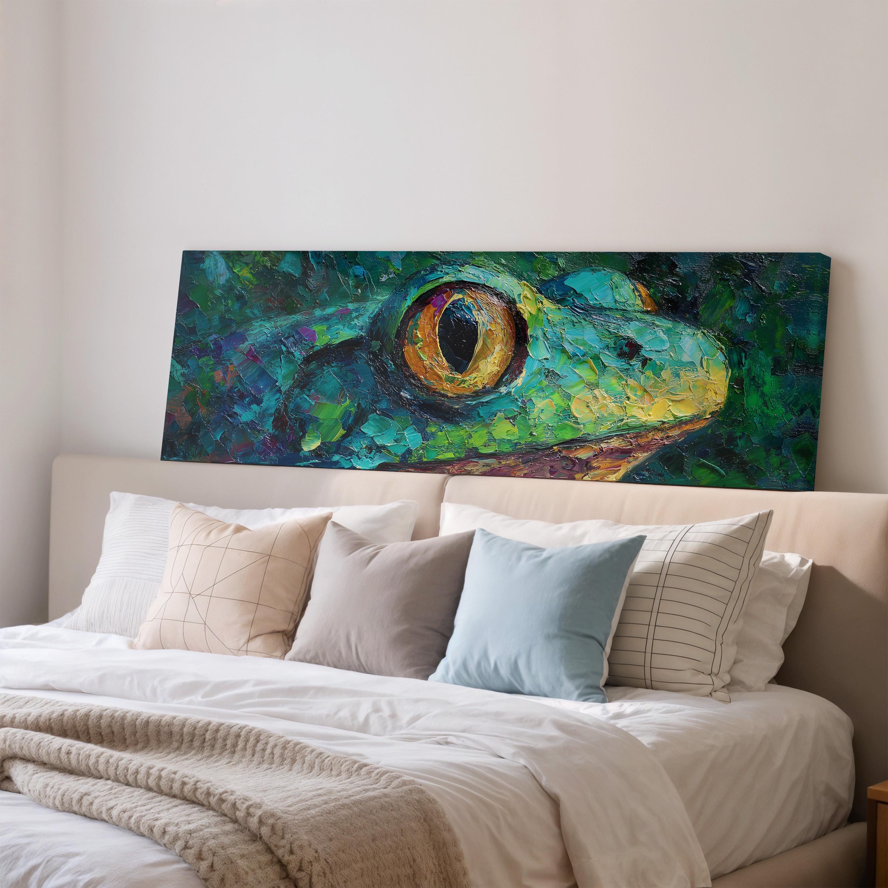 a large, colorful painting of a frog's face hanging on a wall above a bed with white pillows and a gray blanket.