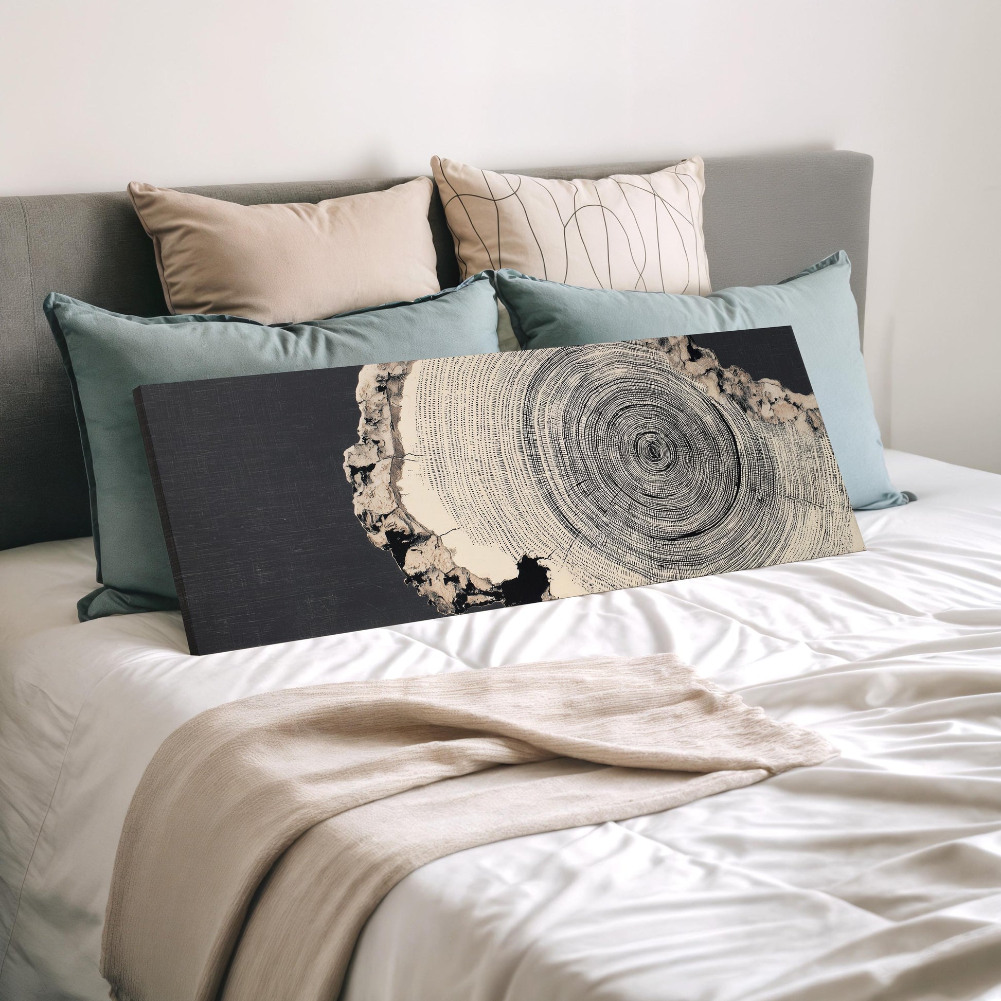 a bedroom with a bed covered in white sheets and a black and white abstract artwork displayed on the bed.
