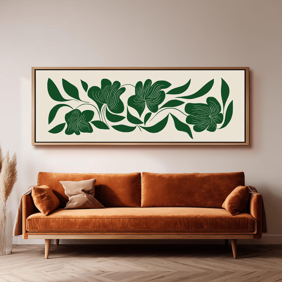a large, framed artwork of green leaves and flowers hanging on a wall above a brown sofa.