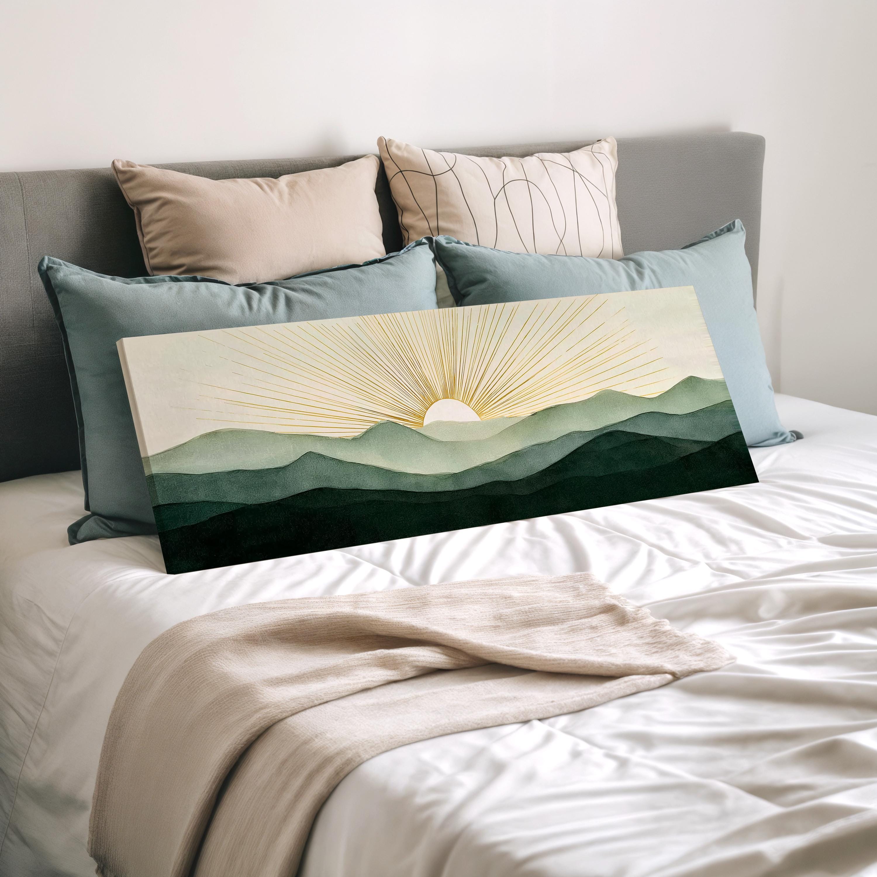 a bedroom with a bed covered in white sheets and a large canvas print of a mountain landscape with a sunburst design on the right side.