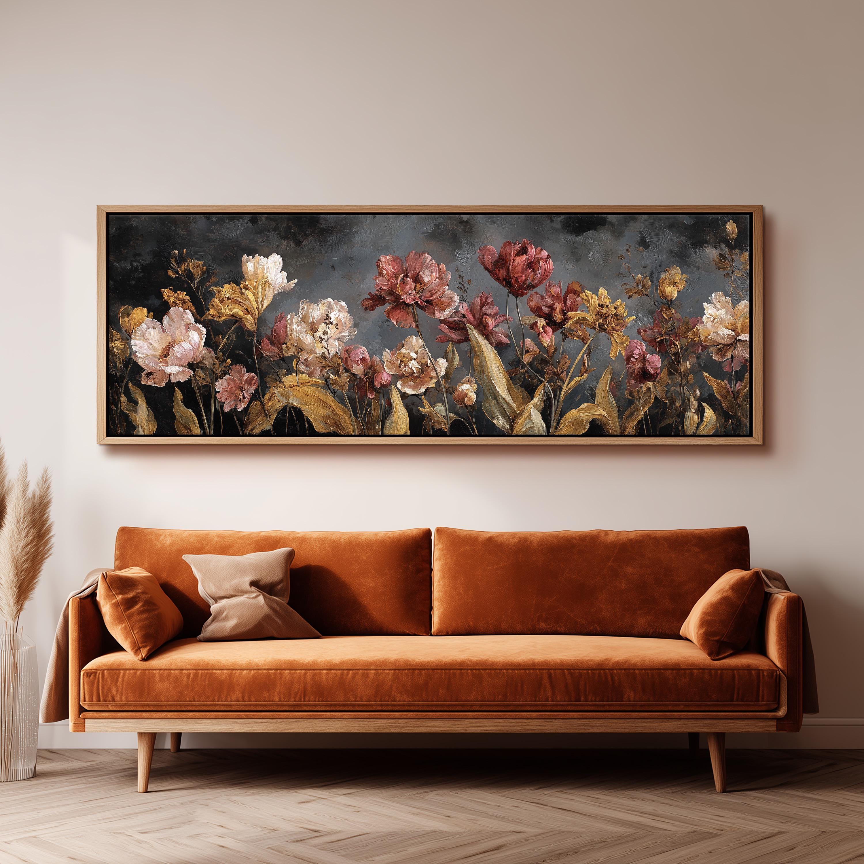 a large, framed painting of flowers hanging on a wall above a brown sofa.