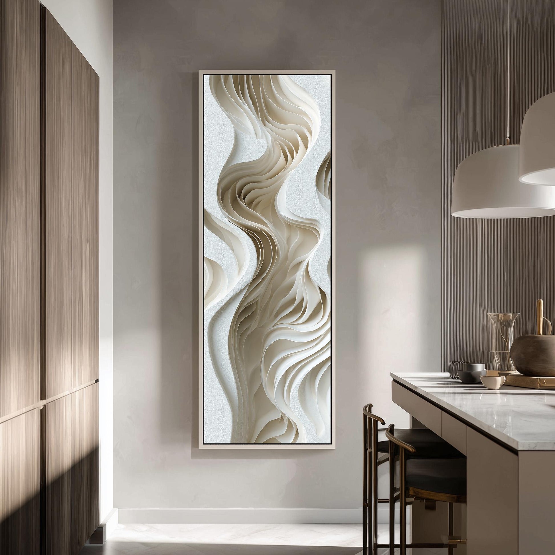 a modern kitchen with a large abstract artwork hanging on the wall. The artwork has a swirling, organic design in shades of white and beige, creating a sense of movement and fluidity. The kitchen is well-lit, with a pendant light hanging above the countertop and a wooden cabinet visible on the left side of the image.
