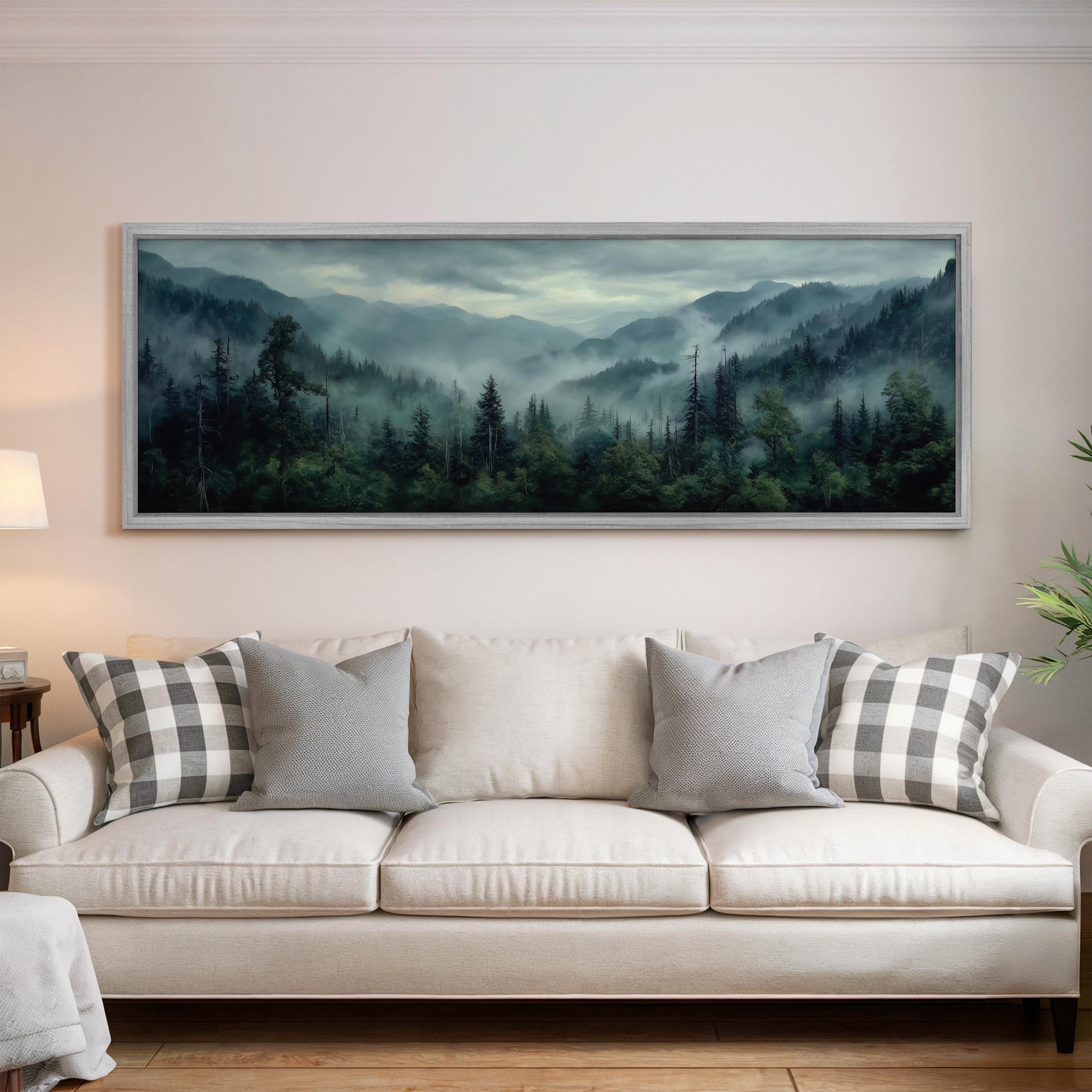 a large landscape painting hanging on a wall above a white sofa with gray and white patterned pillows.