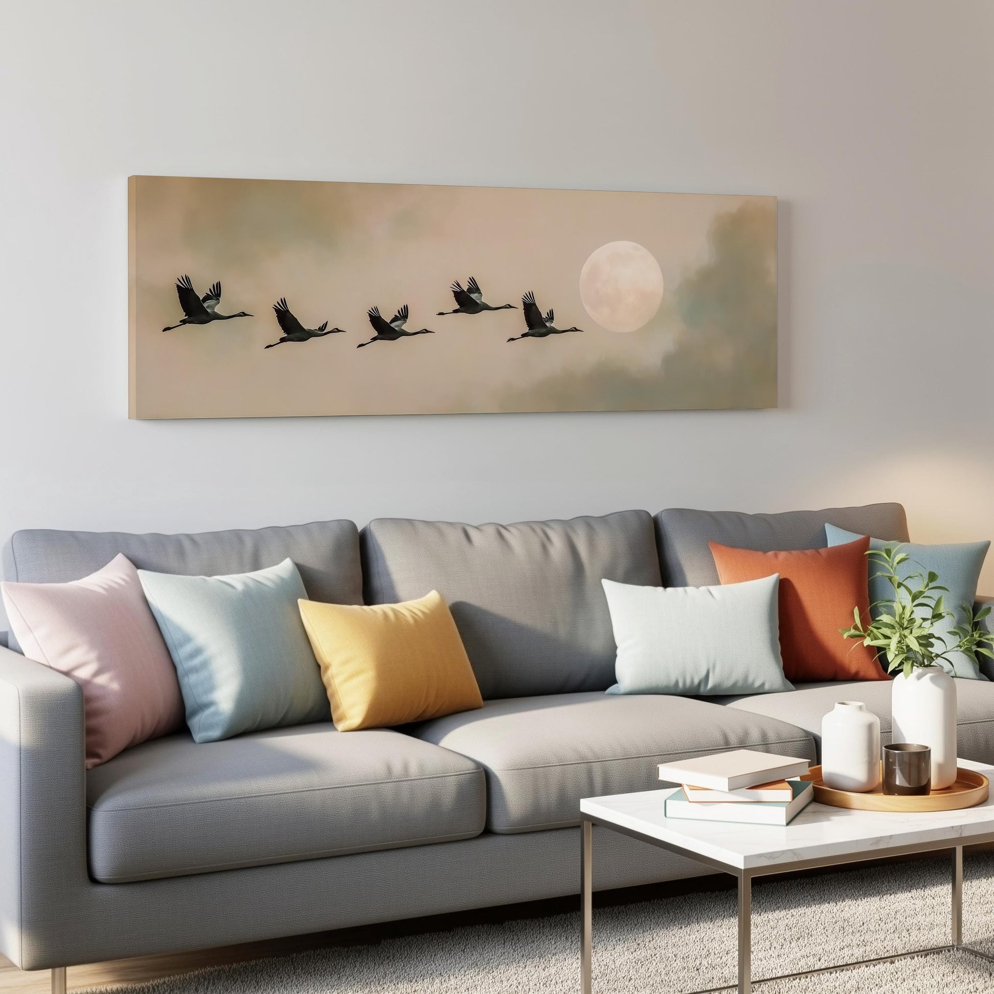 a gray couch with colorful throw pillows, a coffee table, and a painting of a flock of birds flying in formation above it.