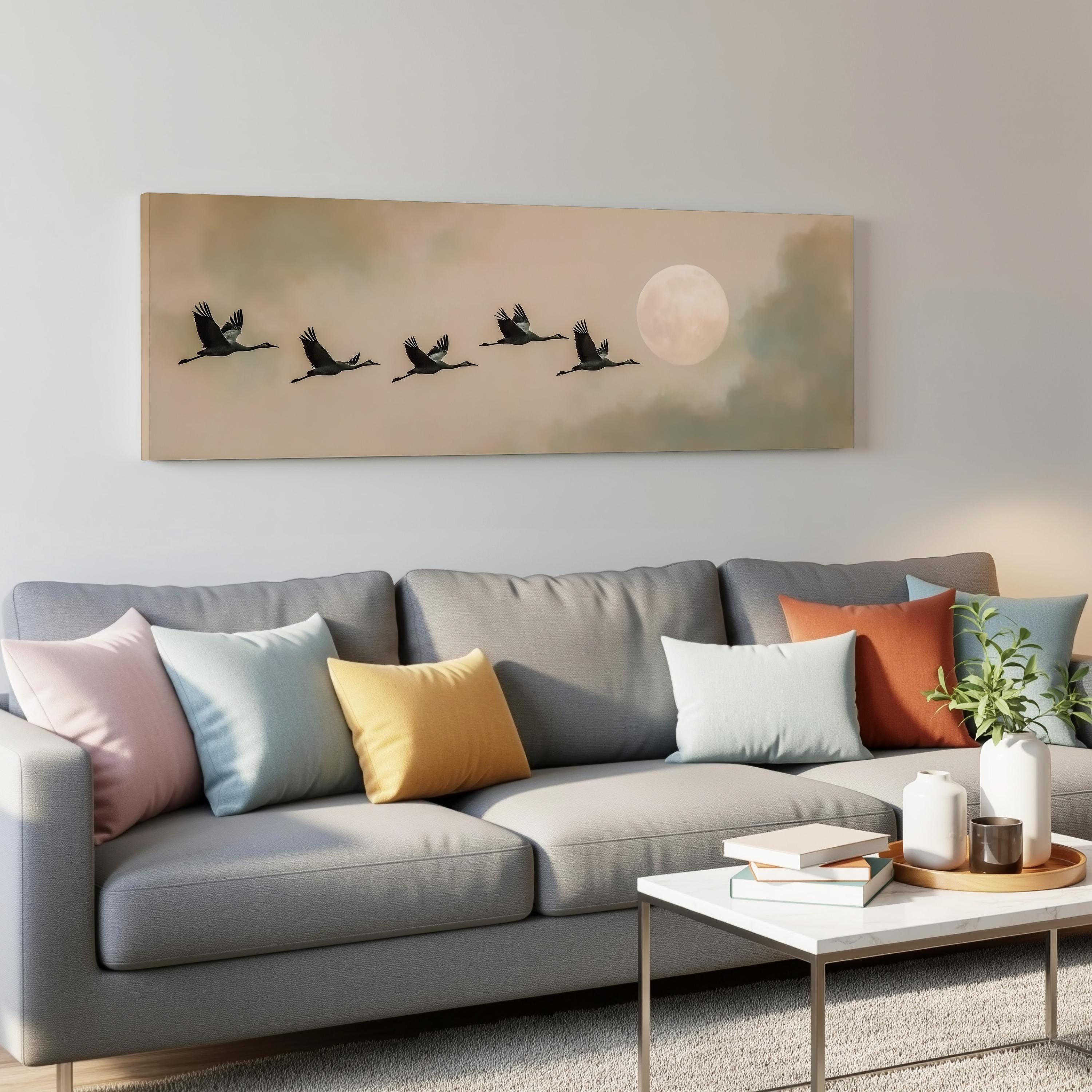 a gray couch with colorful throw pillows, a coffee table, and a painting of a flock of birds flying in formation above it.