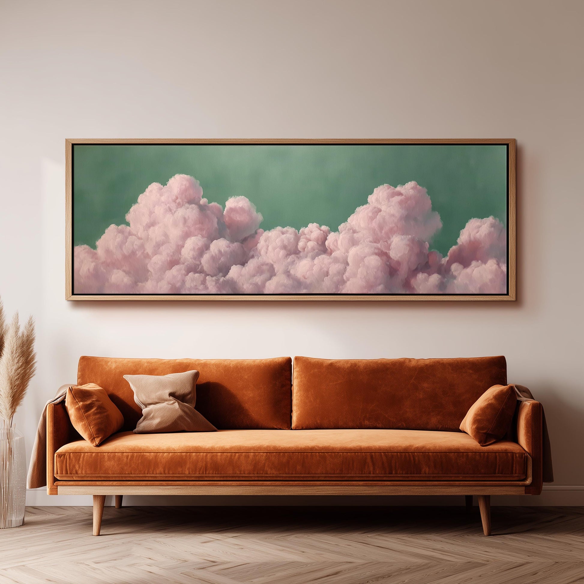 a large, framed picture of pink clouds hanging on a wall above a brown sofa.