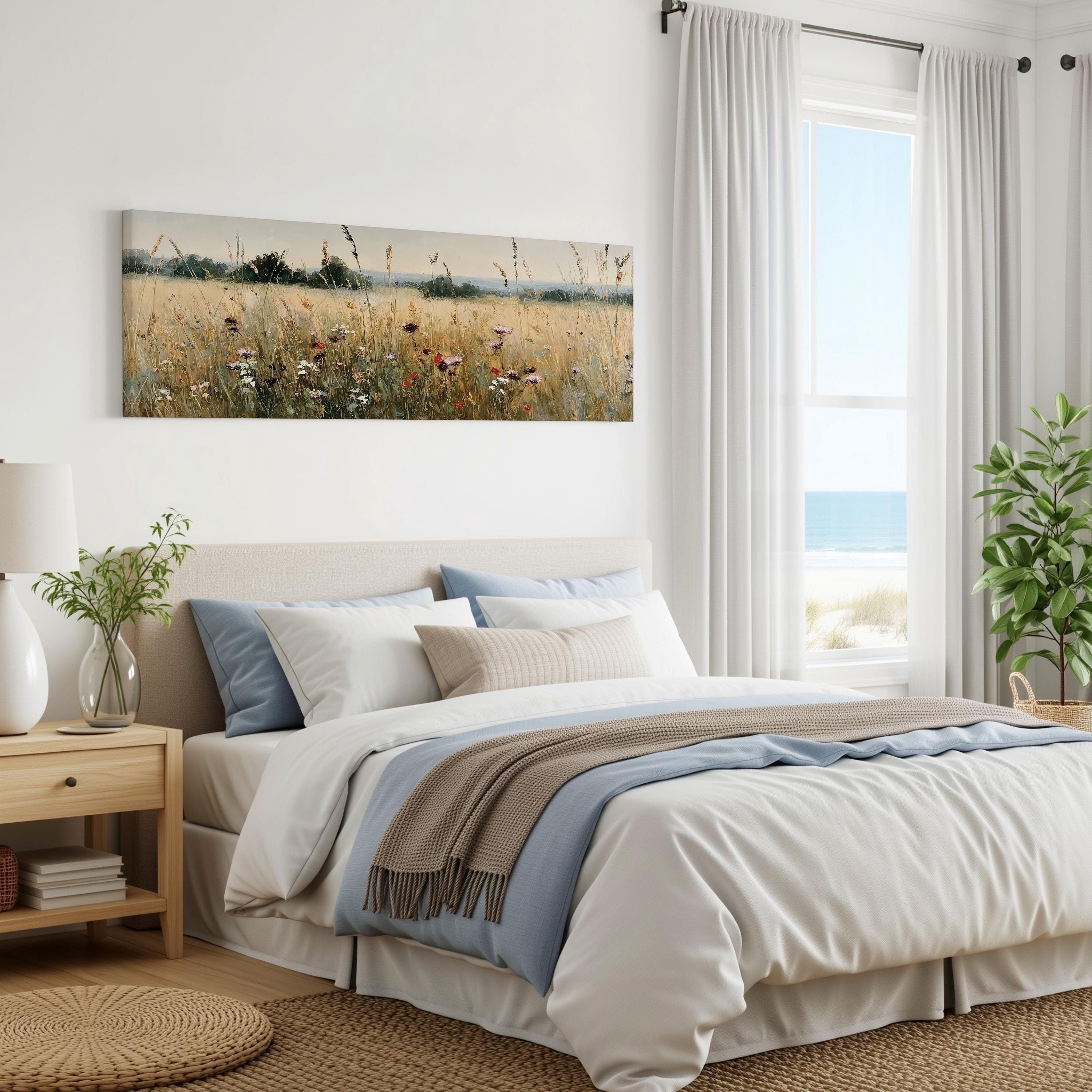 a serene bedroom with a large bed, a nightstand, and a painting of a field of flowers on the wall. The room has a calming and peaceful atmosphere, with natural light coming in through the window overlooking the beach.