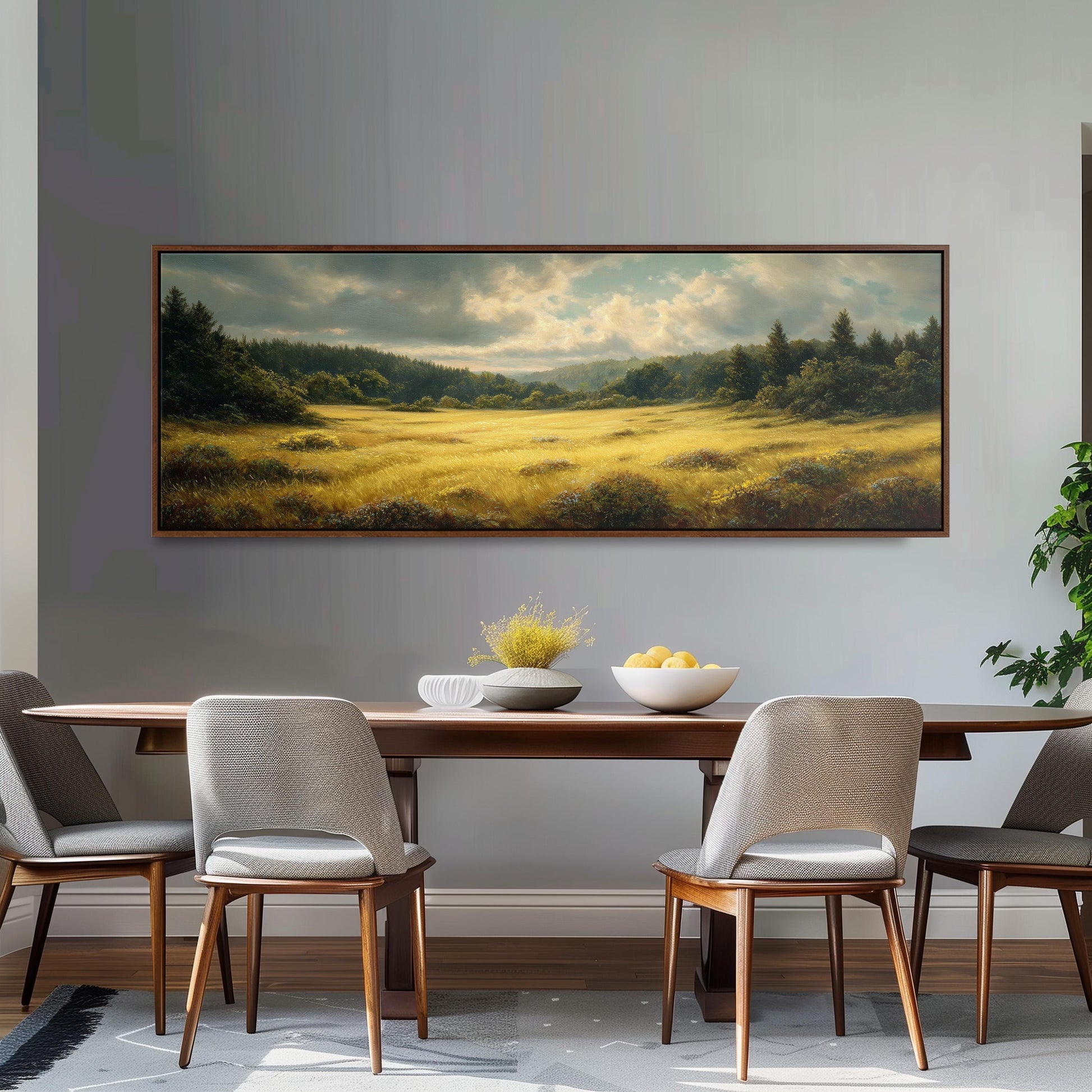 a dining room with a large painting of a field hanging on the wall above a wooden table with four chairs. The table is set with a bowl of fruit and a vase of flowers, creating a cozy and inviting atmosphere.