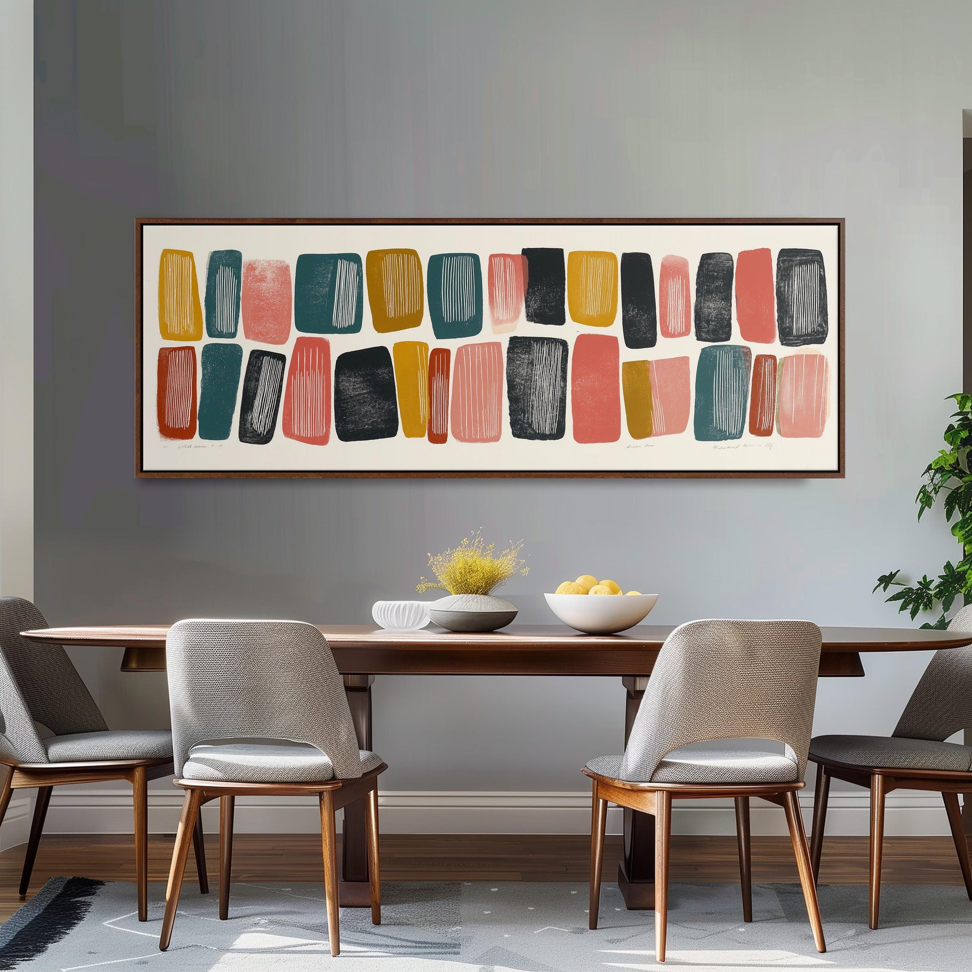 a modern dining room with a wooden table and four chairs. Above the table, there is a large abstract painting with various shapes and colors. The table is set with a bowl of fruit and a vase of flowers, creating a welcoming and stylish atmosphere.