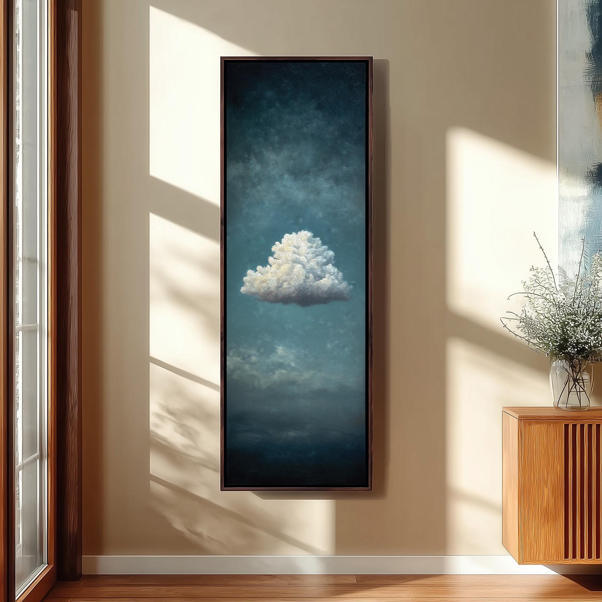 a large framed painting of a cloud hanging on a wall in a room with a wooden cabinet and a vase of flowers.