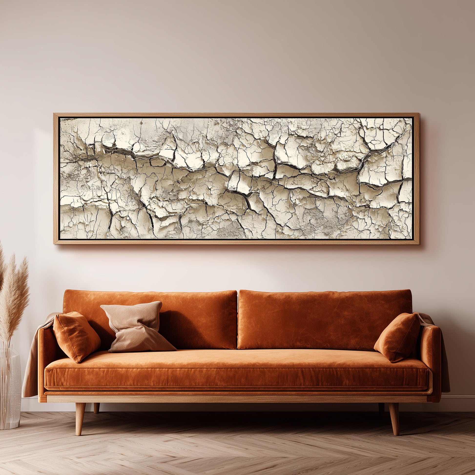 a large, rectangular, and dark brown couch with a wooden frame, positioned in front of a white wall. Above the couch, there is a framed artwork depicting a cracked and weathered surface.