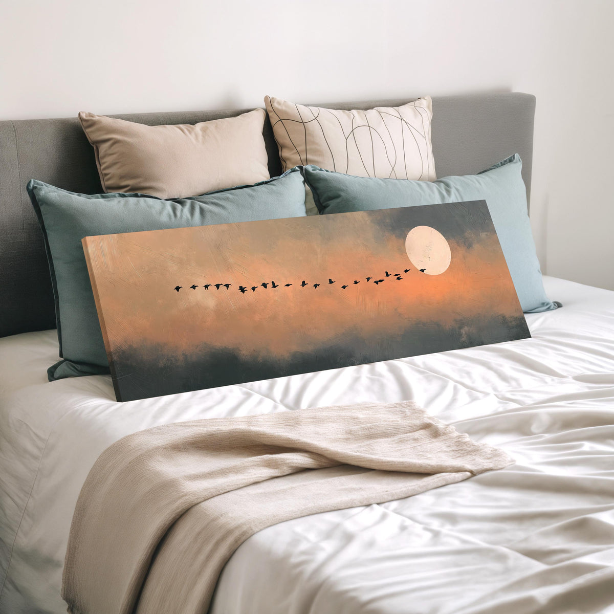 Geese flying toward the moon at twilight wide panoramic canvas print laid on a bed to show its size