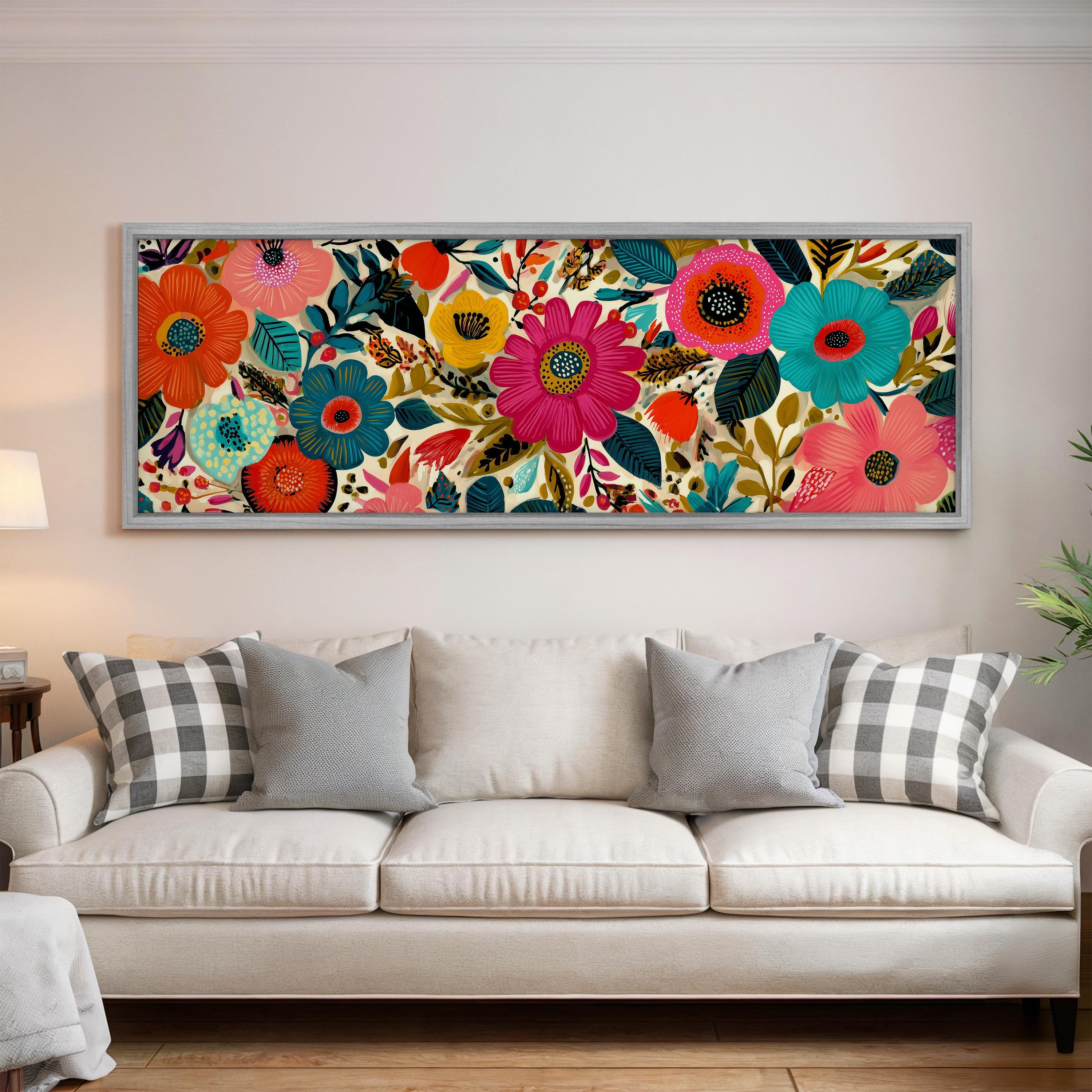 a large, colorful floral print hanging on a wall above a white couch with gray and white plaid throw pillows.