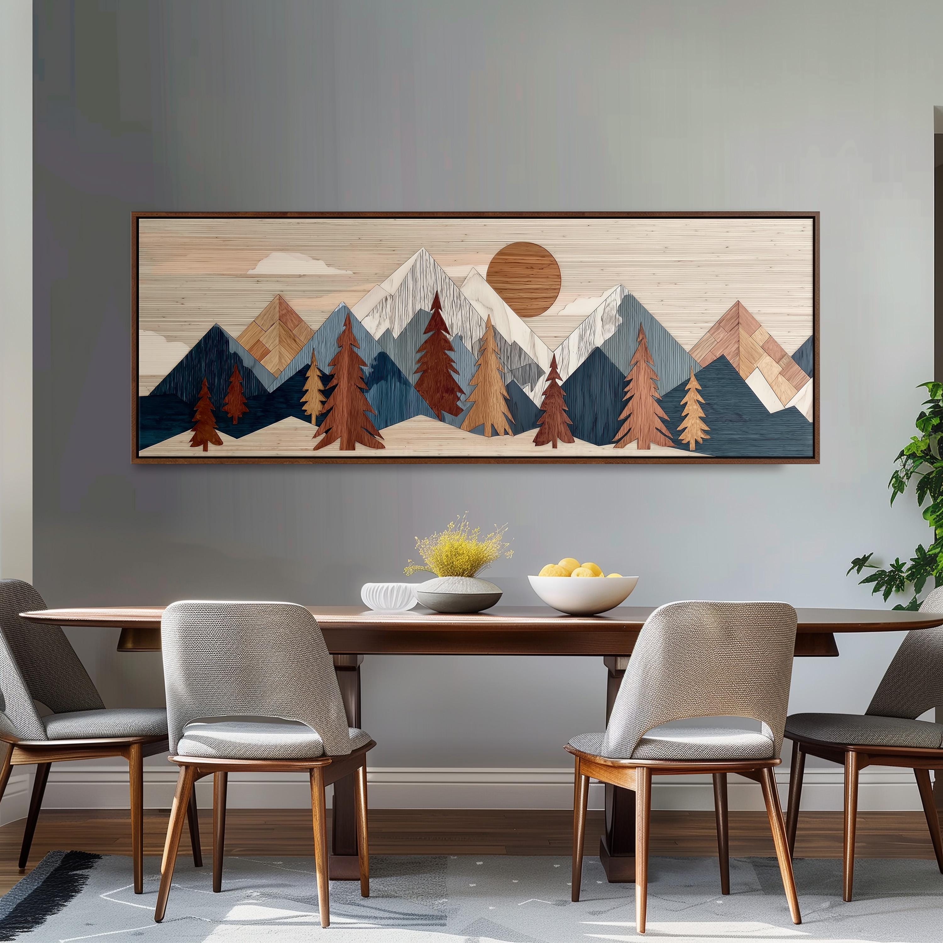 a dining room with a wooden table and four chairs. Above the table, there is a large framed artwork depicting a mountain landscape with a sun and clouds. The artwork is hanging on a gray wall.