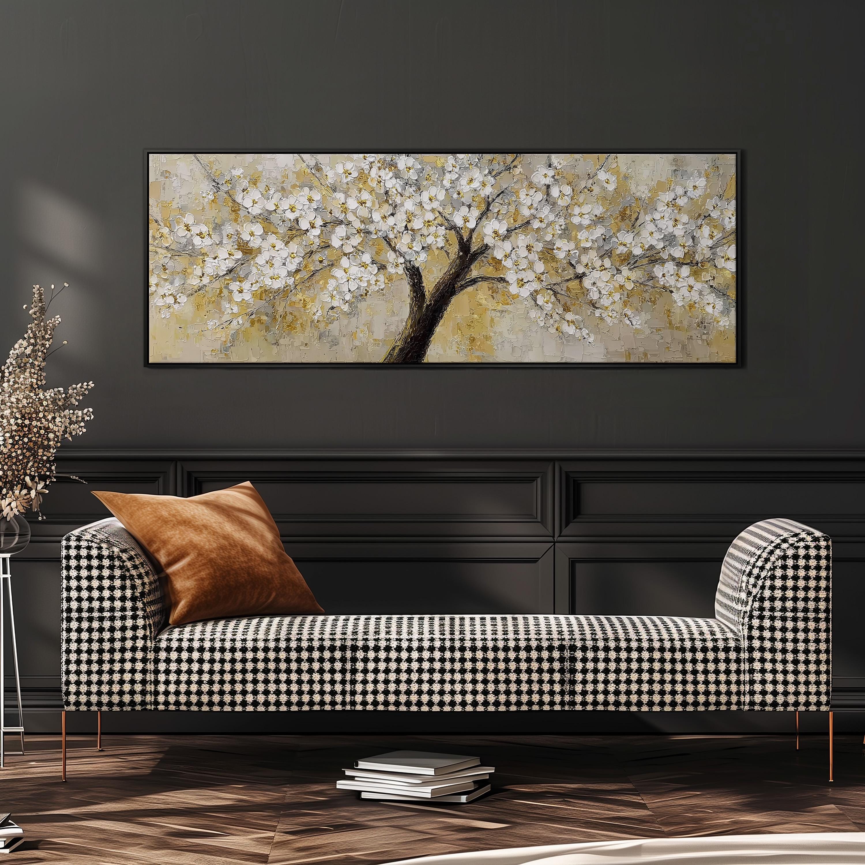 a large painting of a tree with white flowers hanging on a wall above a black and white checkered sofa with a brown throw pillow.