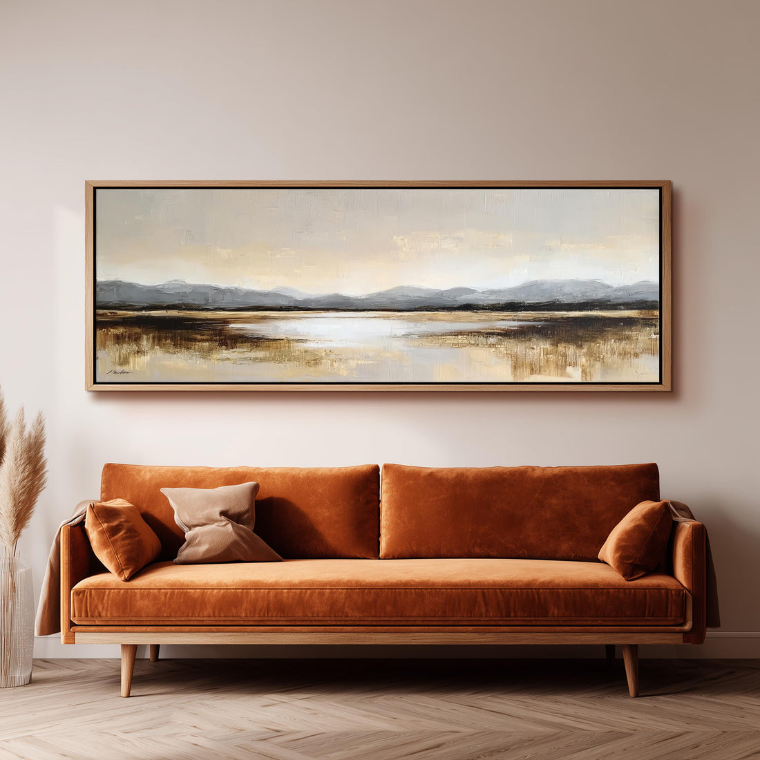 a large landscape painting hanging on a wall above a brown sofa with orange cushions.