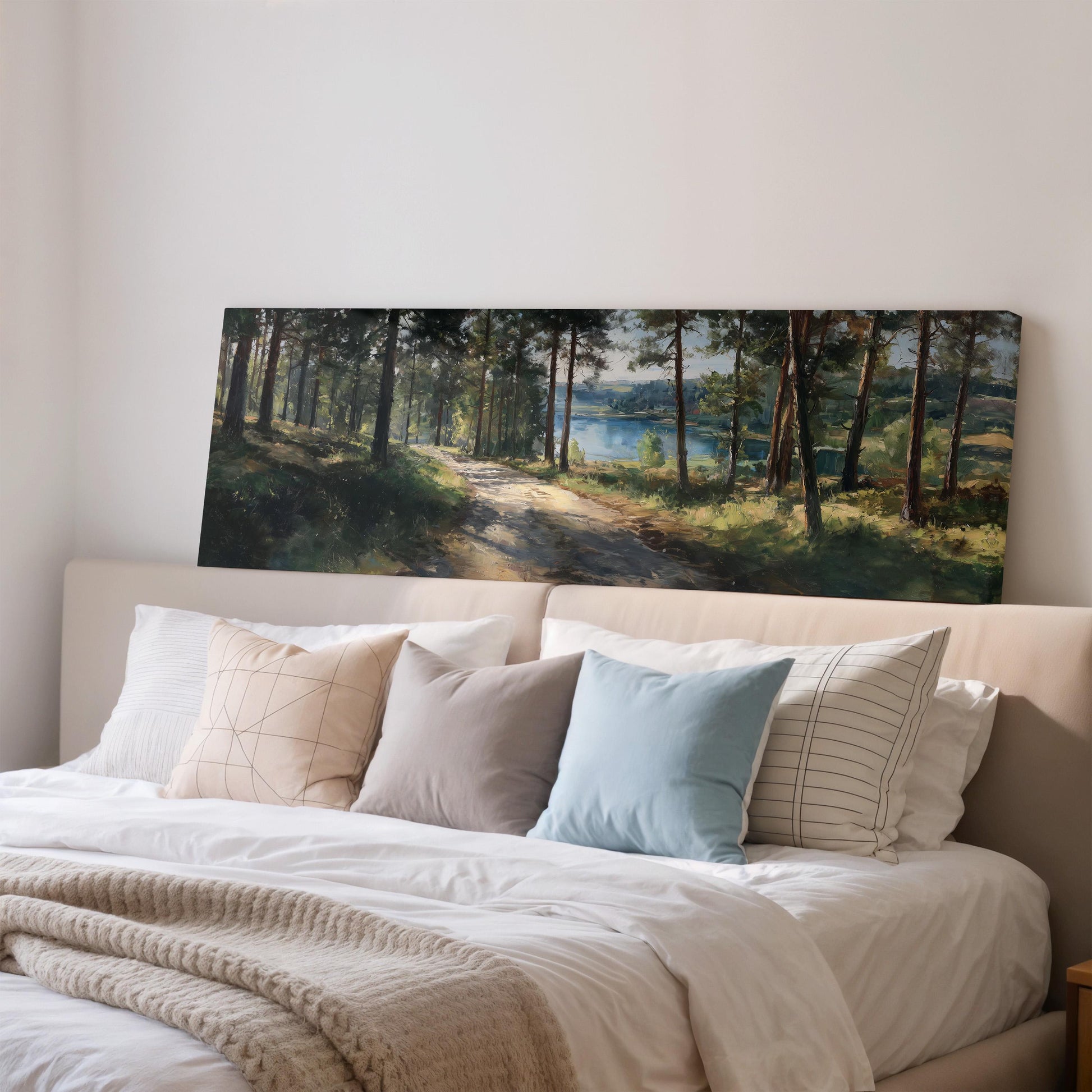 a large painting of a forest scene hanging on a wall above a bed with white bedding and pillows.
