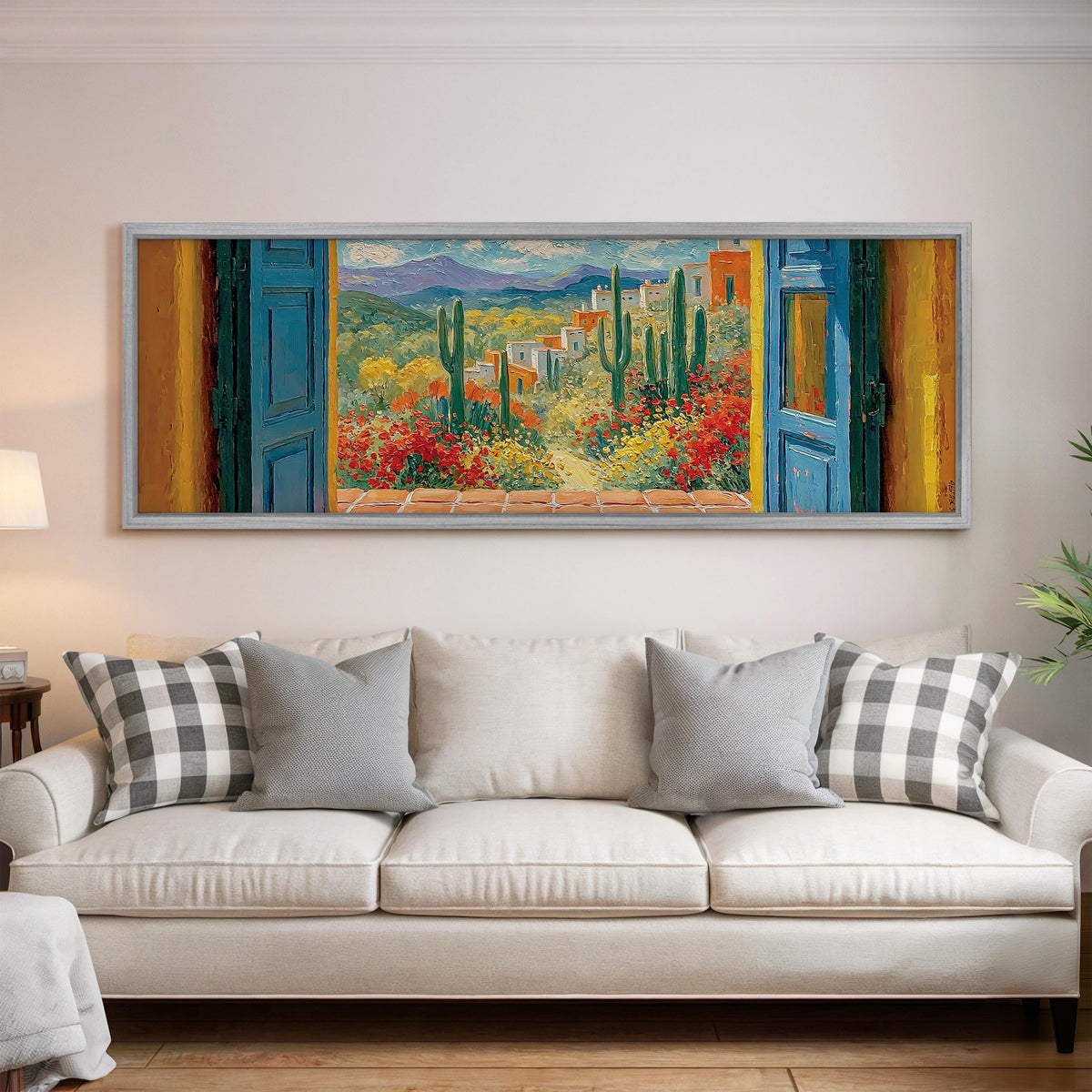 Cactus courtyard seen through blue doors panoramic canvas print above a white sofa in a bright living room