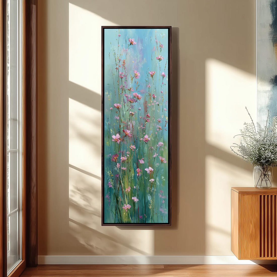 a large painting of pink flowers hanging on a wall in a room with a wooden cabinet below it.