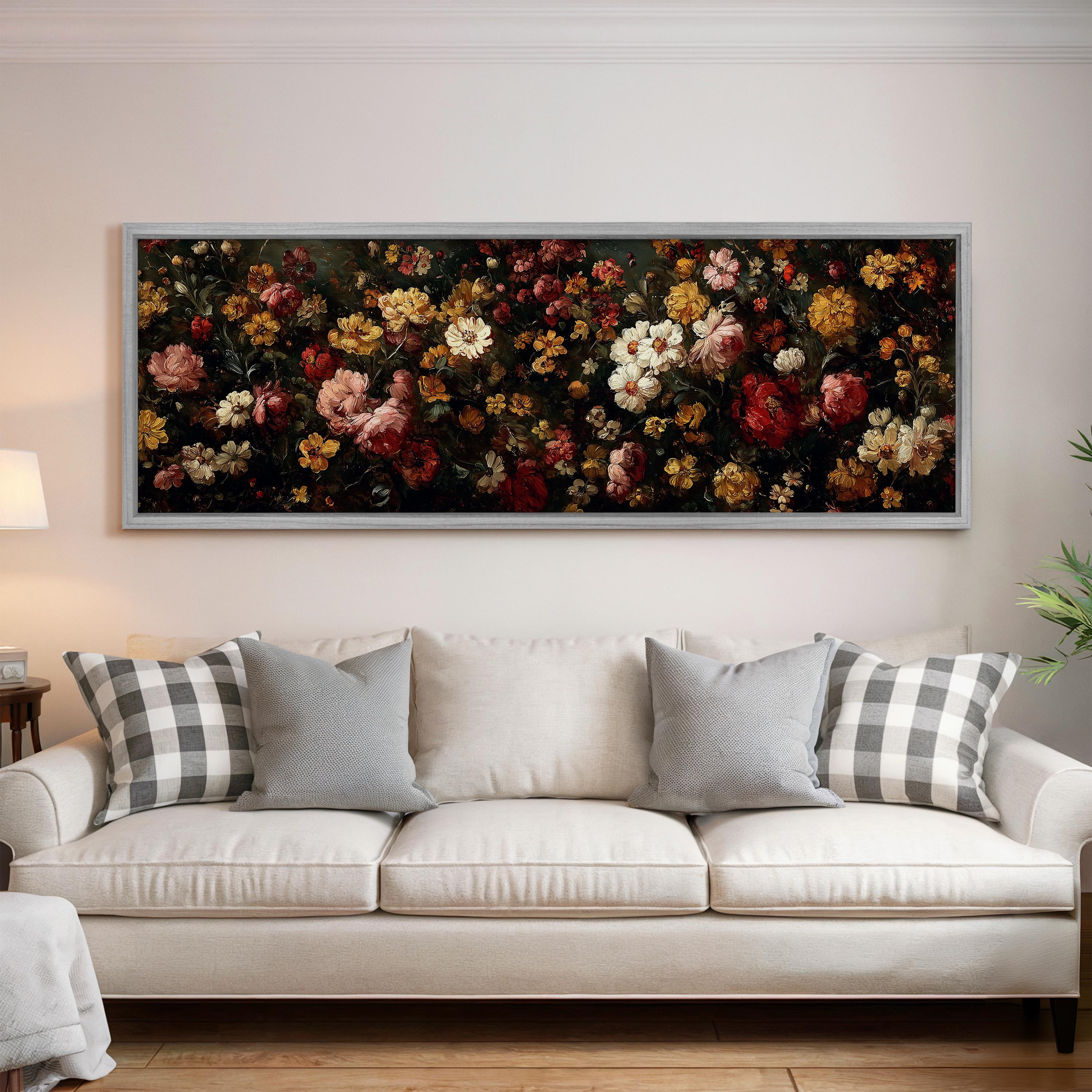 a large, framed painting of a vibrant floral arrangement hanging on a wall above a white couch with gray and white patterned pillows.