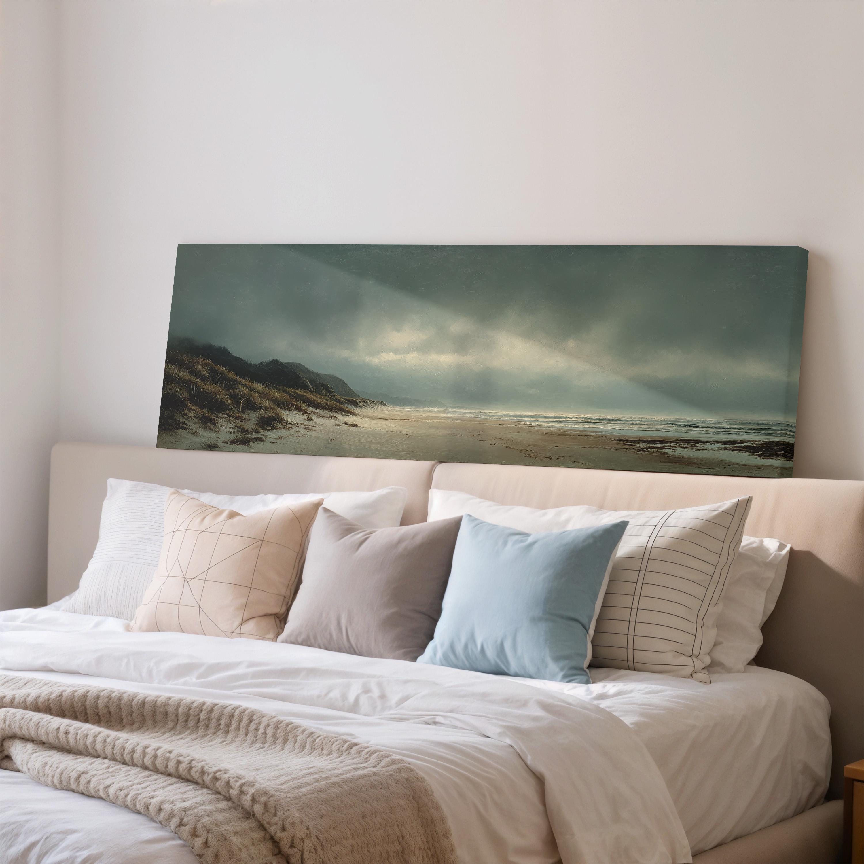 a large painting of a beach scene hanging on a wall above a bed with white bedding and pillows.