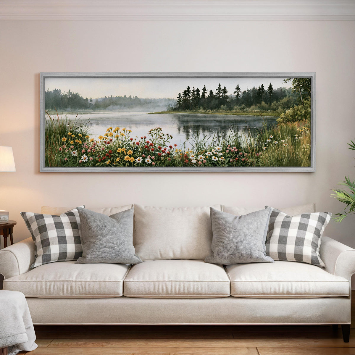 Lake with wildflowers on the shore panoramic canvas print above a white sofa in a bright living room
