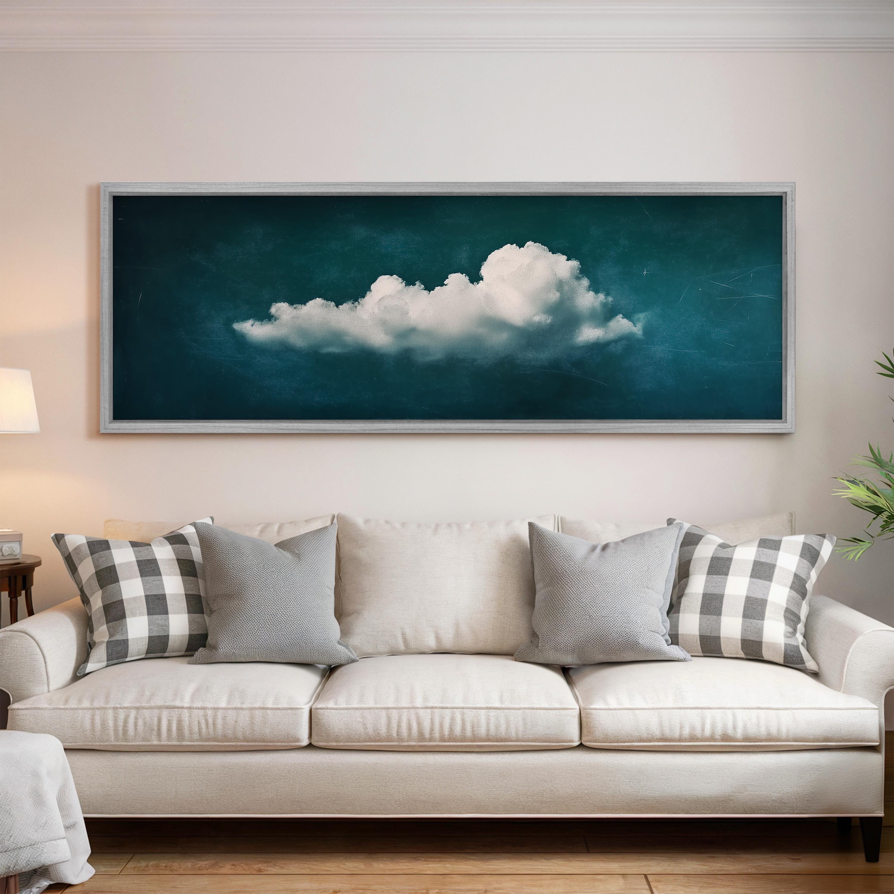 a large framed picture of a cloud hanging on a wall above a white sofa with gray and white plaid throw pillows.