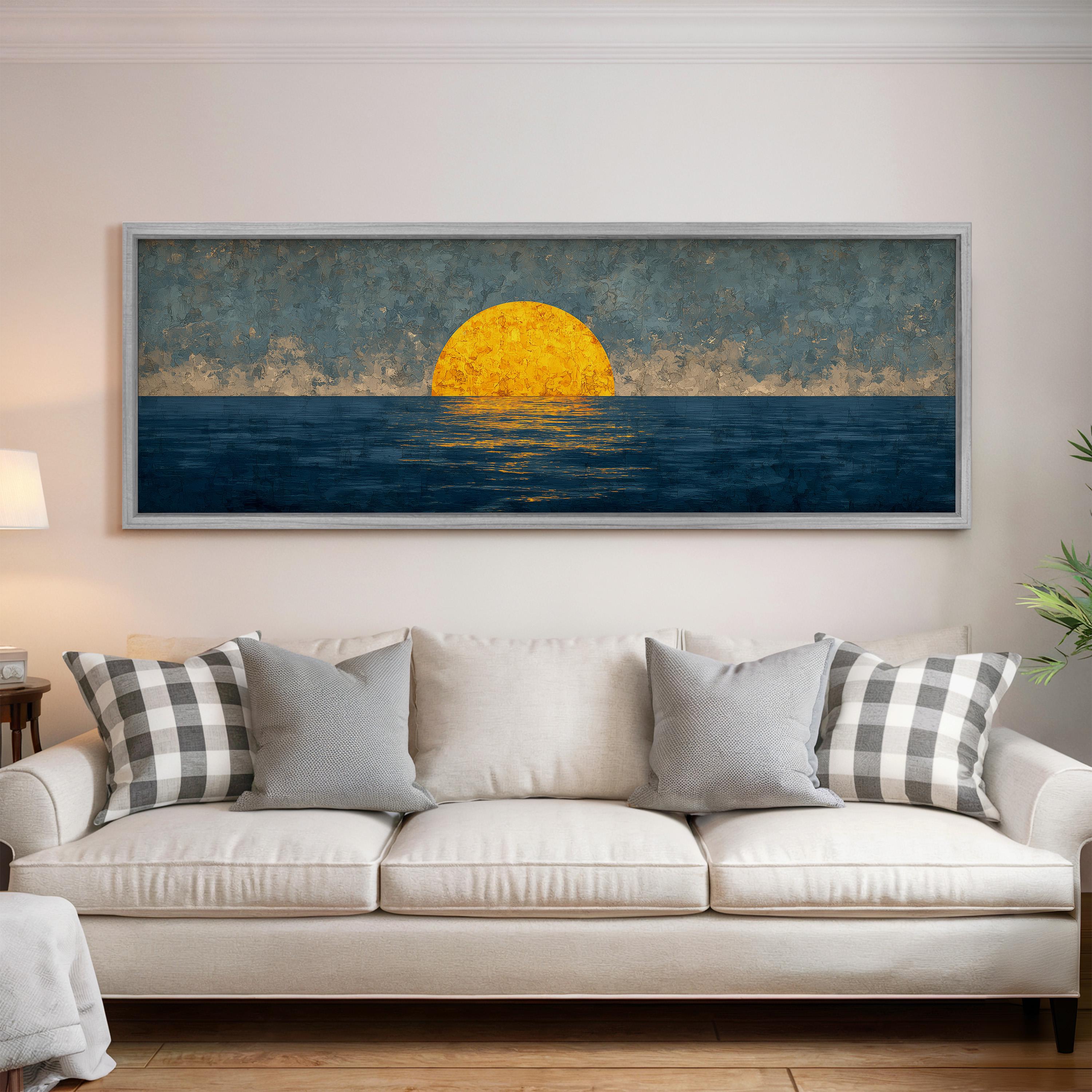 a large painting of a sunset over the ocean, hanging on a wall above a white sofa with gray and white patterned pillows.