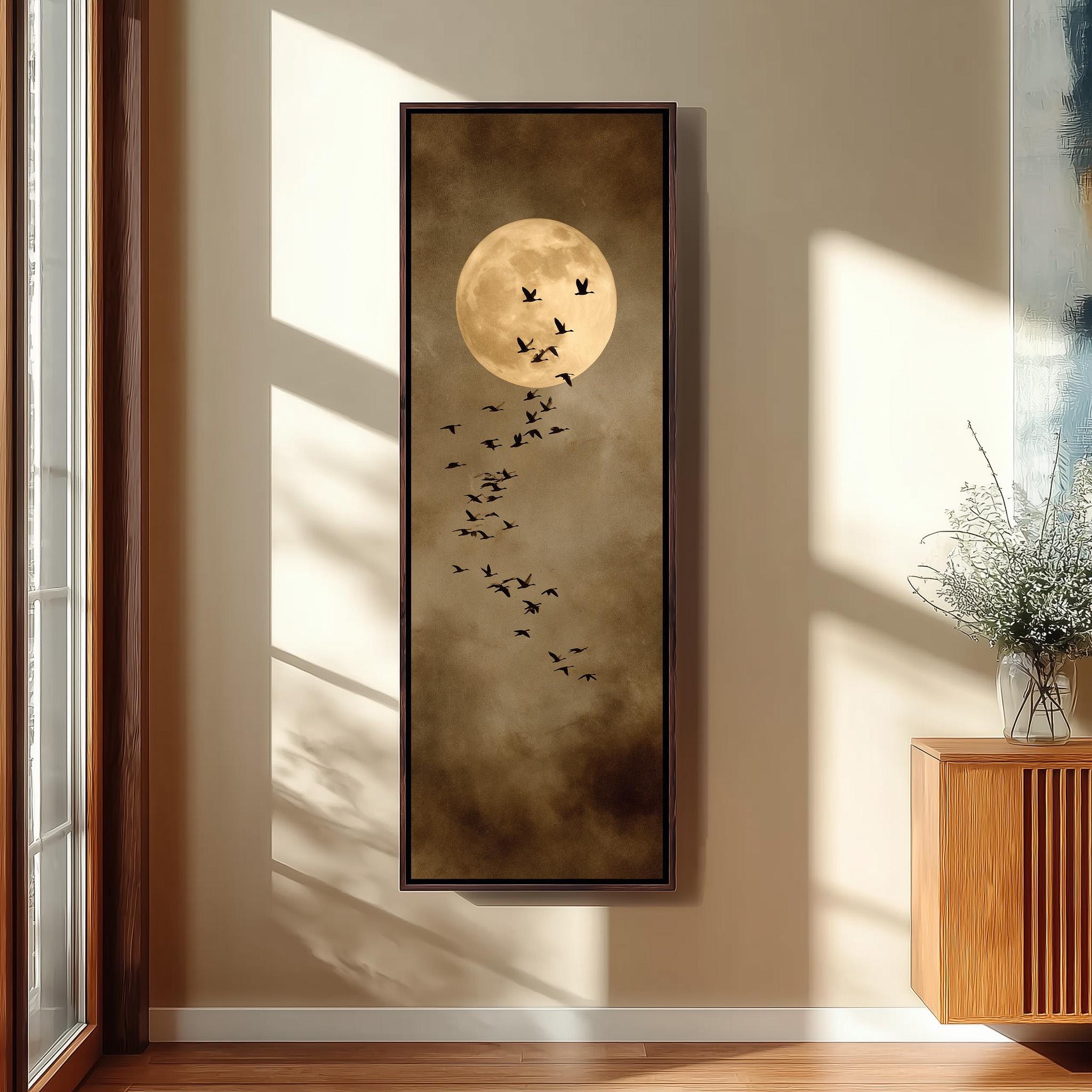 a large framed painting hanging on a wall, depicting a flock of birds flying in the sky with a full moon in the background.