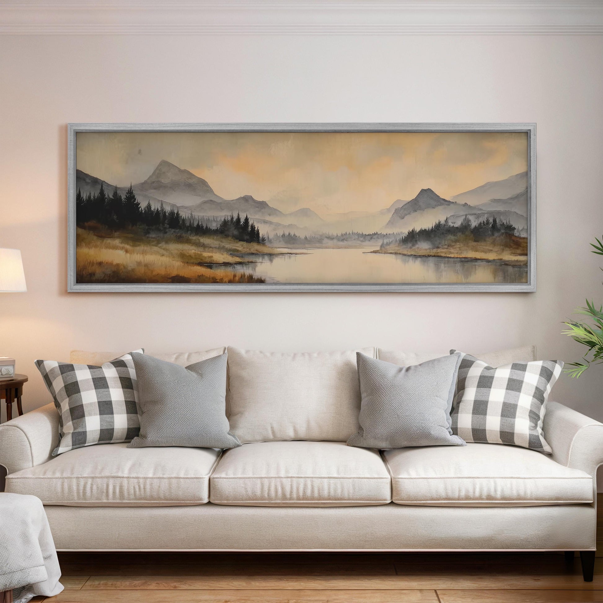 a large landscape painting hanging on a wall above a white sofa with gray and white patterned pillows.