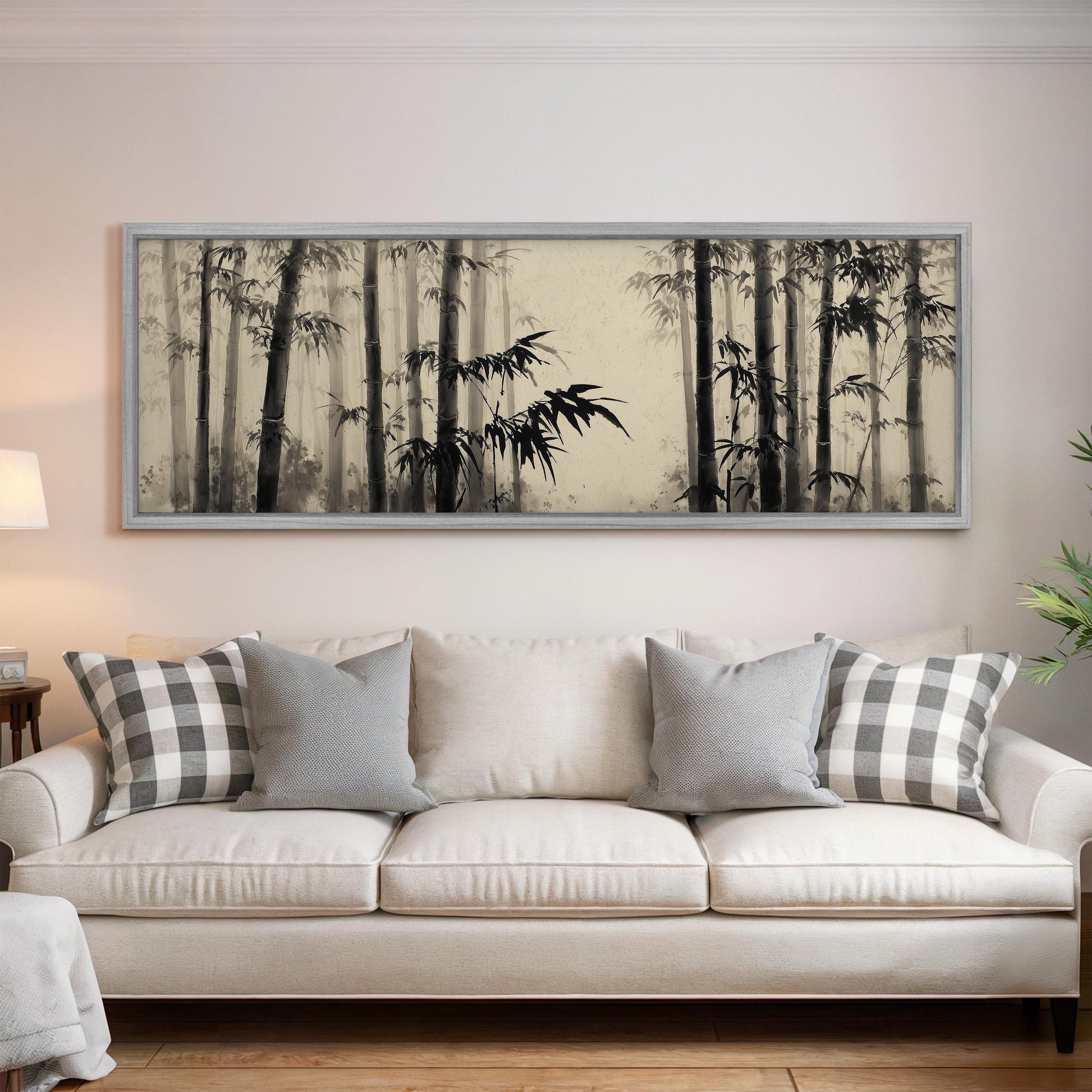 a large black and white painting of bamboo trees hanging on a wall above a white sofa with gray and white patterned pillows.