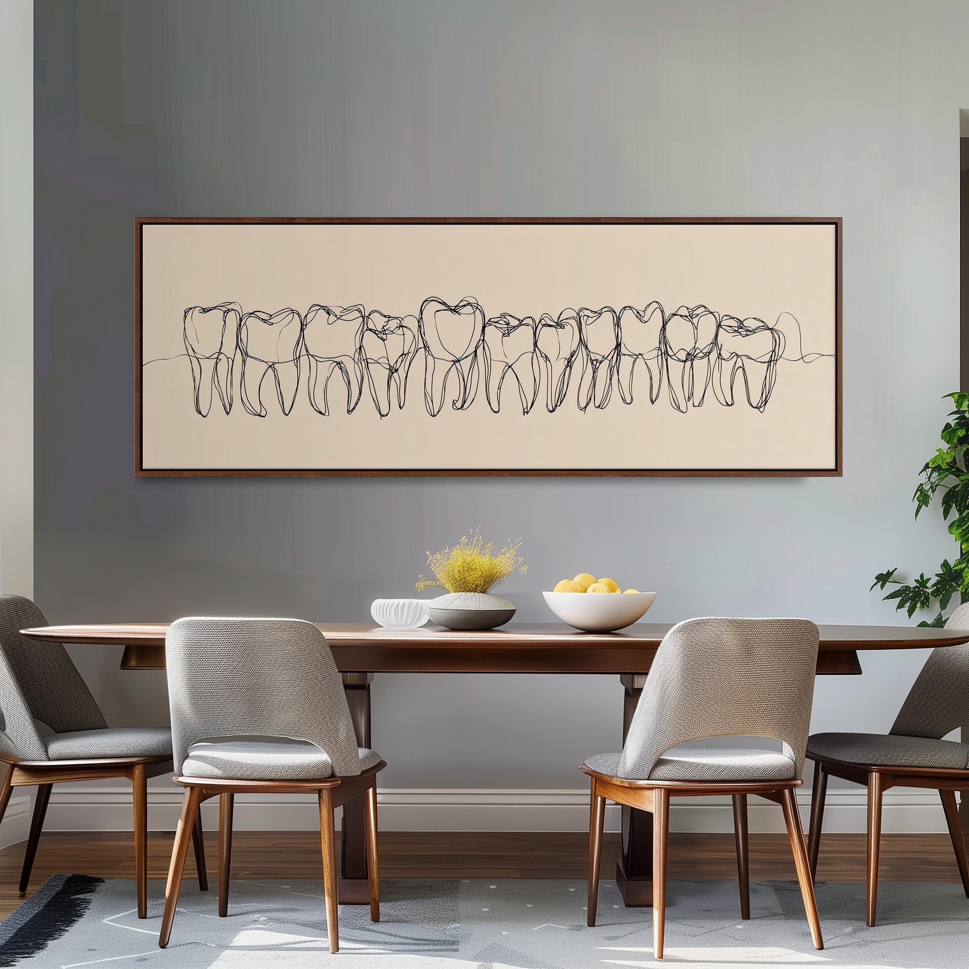 a dining room with a wooden table and four chairs. Above the table, there is a large framed artwork depicting a line of teeth. The table is set with a bowl of fruit and a vase of flowers.