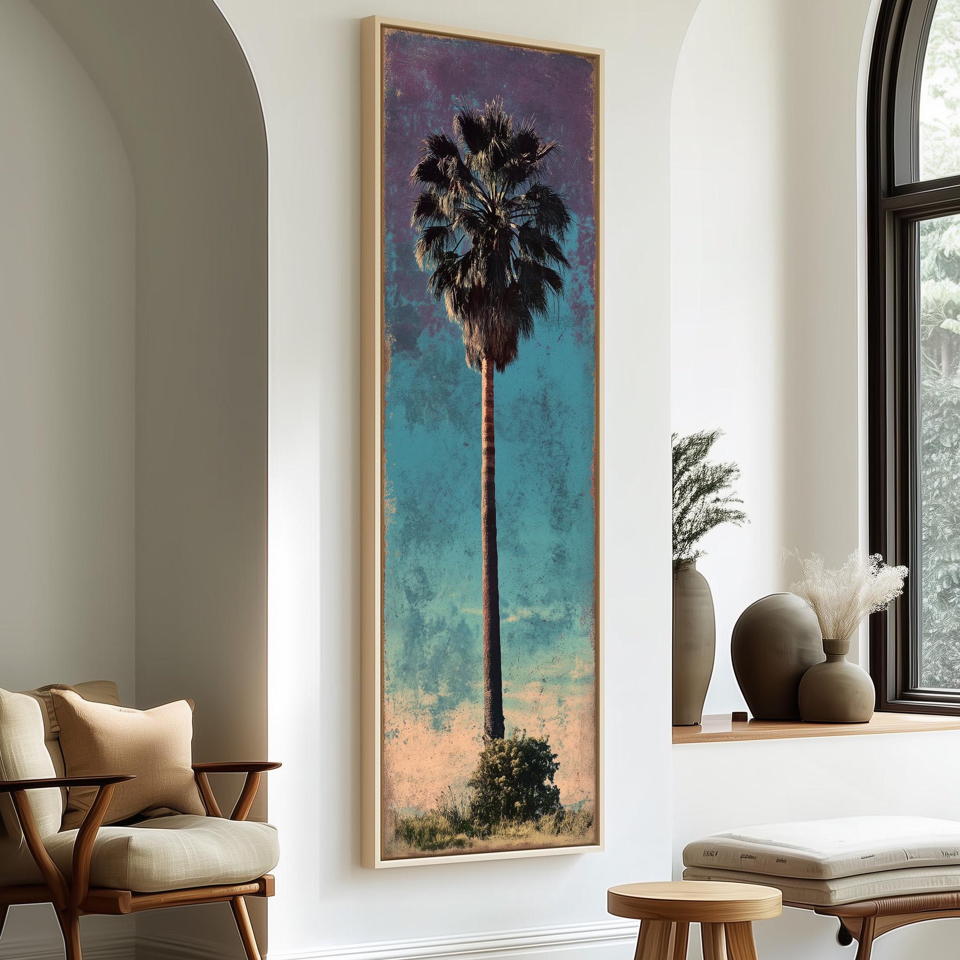a large framed painting of a palm tree hanging on a wall, with a wooden chair and a small table in the foreground.