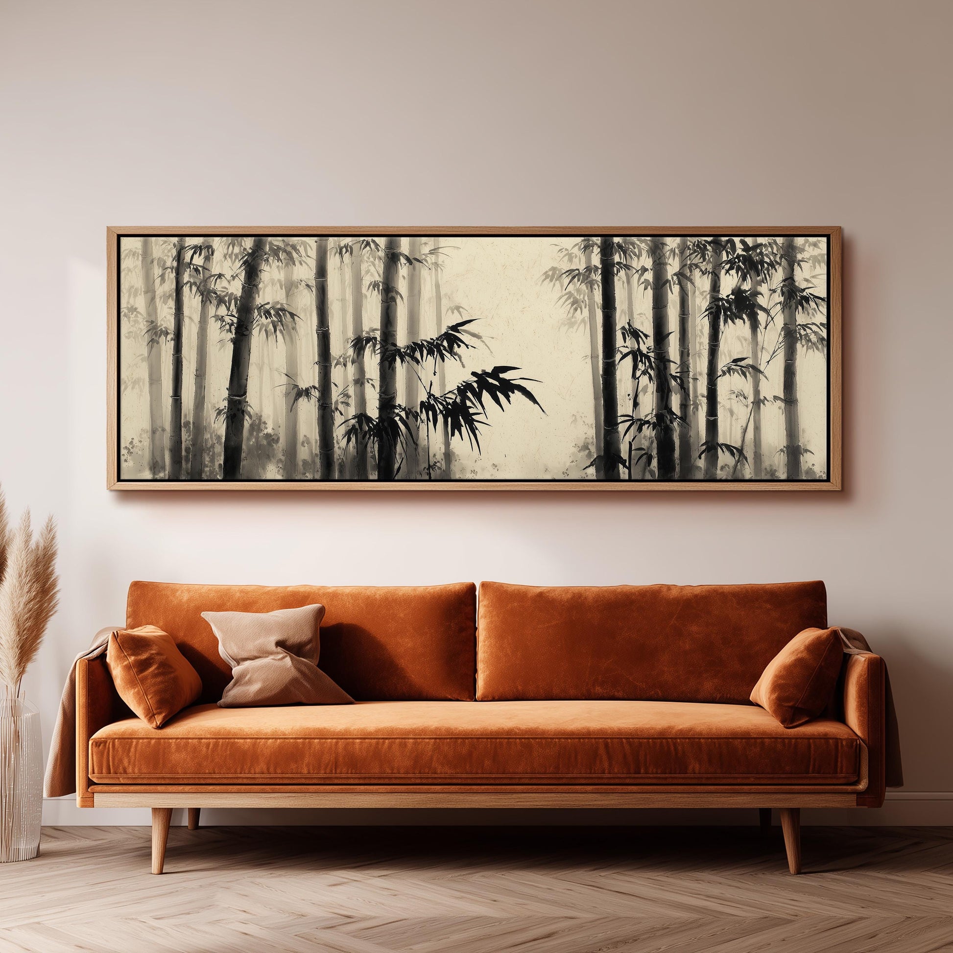 a large black and white painting of bamboo trees hanging on a wall above a brown sofa.