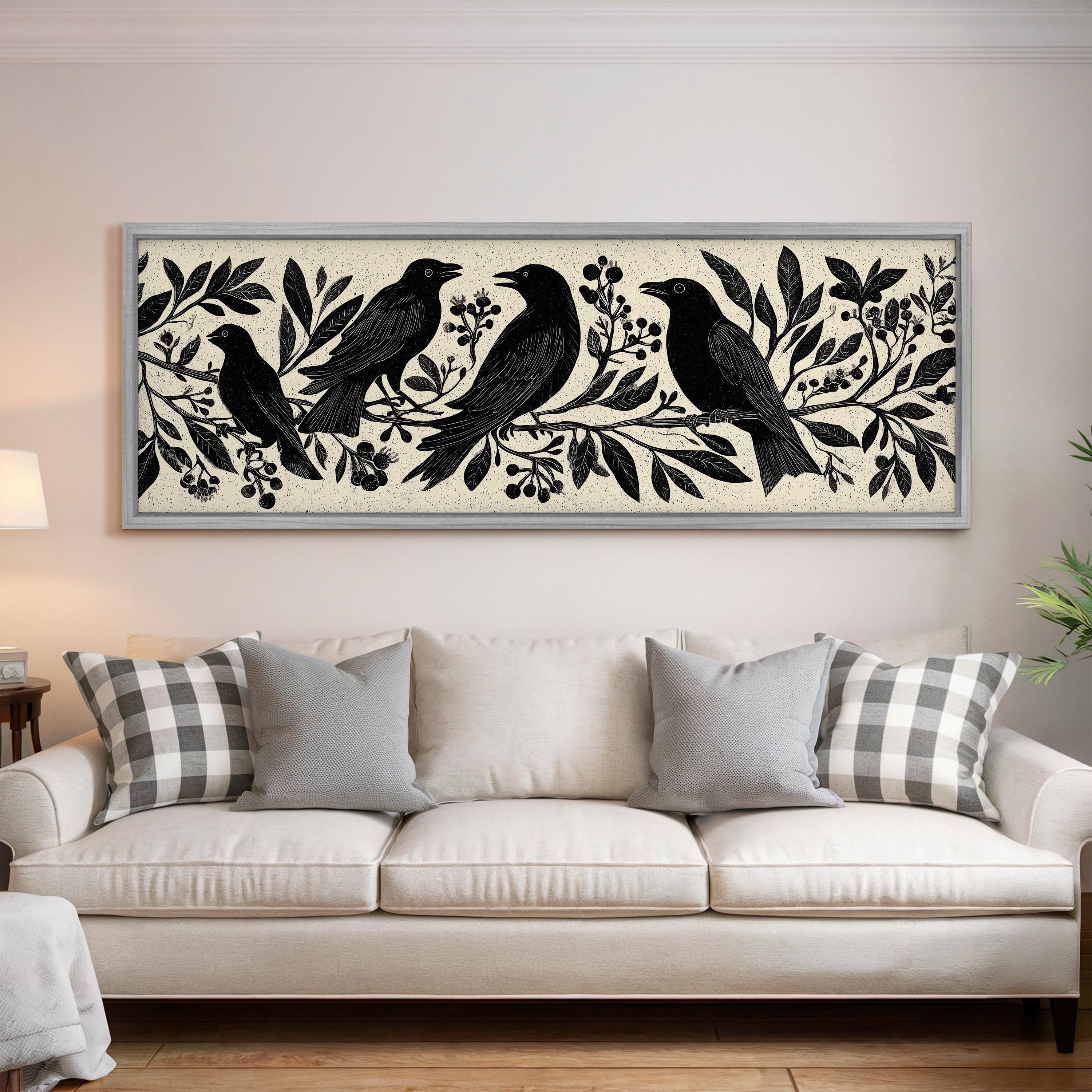 a large framed artwork of black birds perched on branches with leaves and berries, displayed on a wall above a white couch in a living room setting.