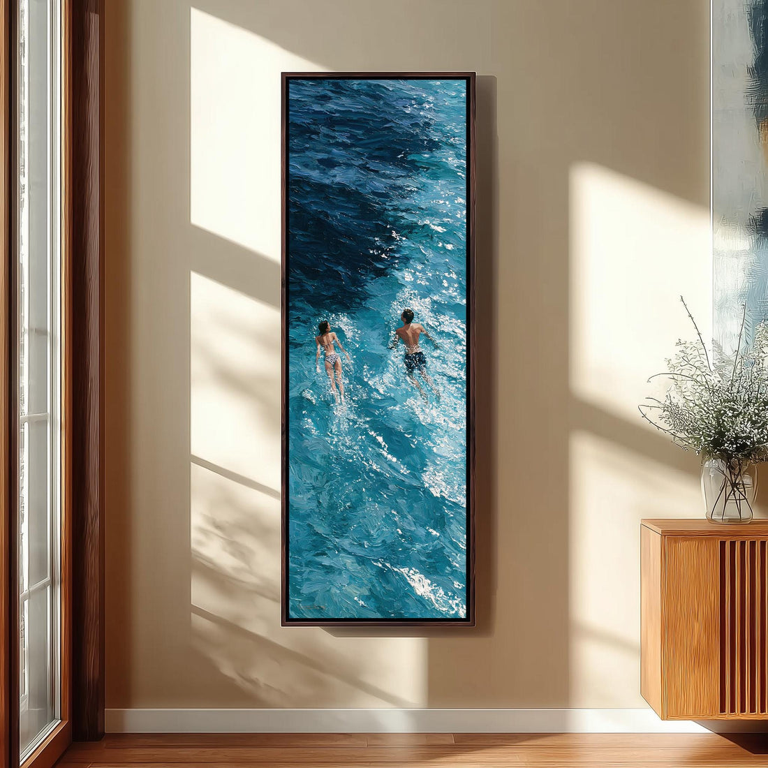 Two swimmers in deep blue waves long vertical canvas print in a sunlit living space