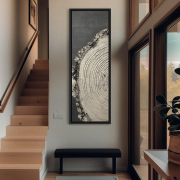 a hallway with a large tree trunk painting hanging on the wall, a wooden staircase, a black bench, and a potted plant.