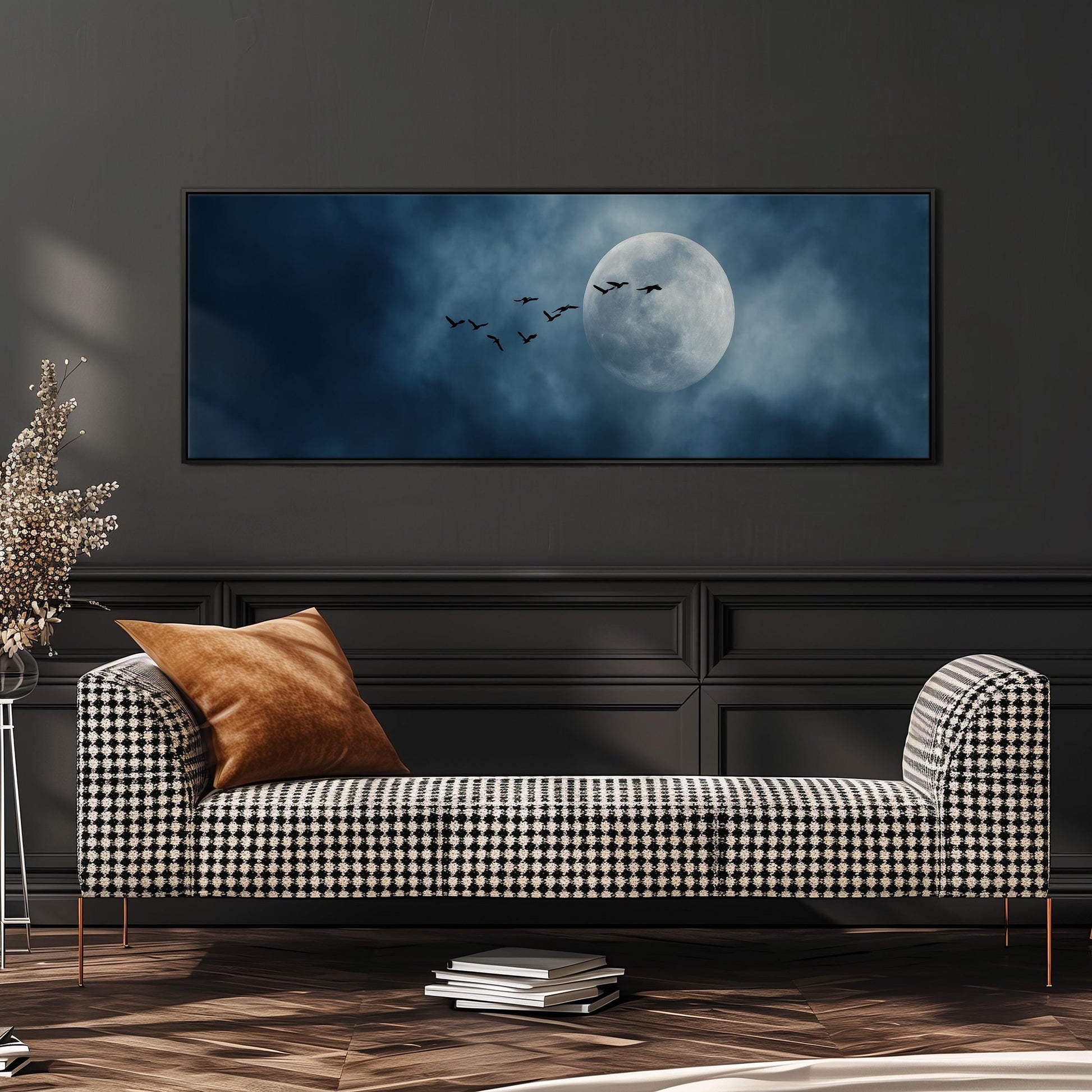 a large black and white checkered sofa with a brown throw pillow, positioned in front of a wall with a framed image of a full moon and a flock of birds.