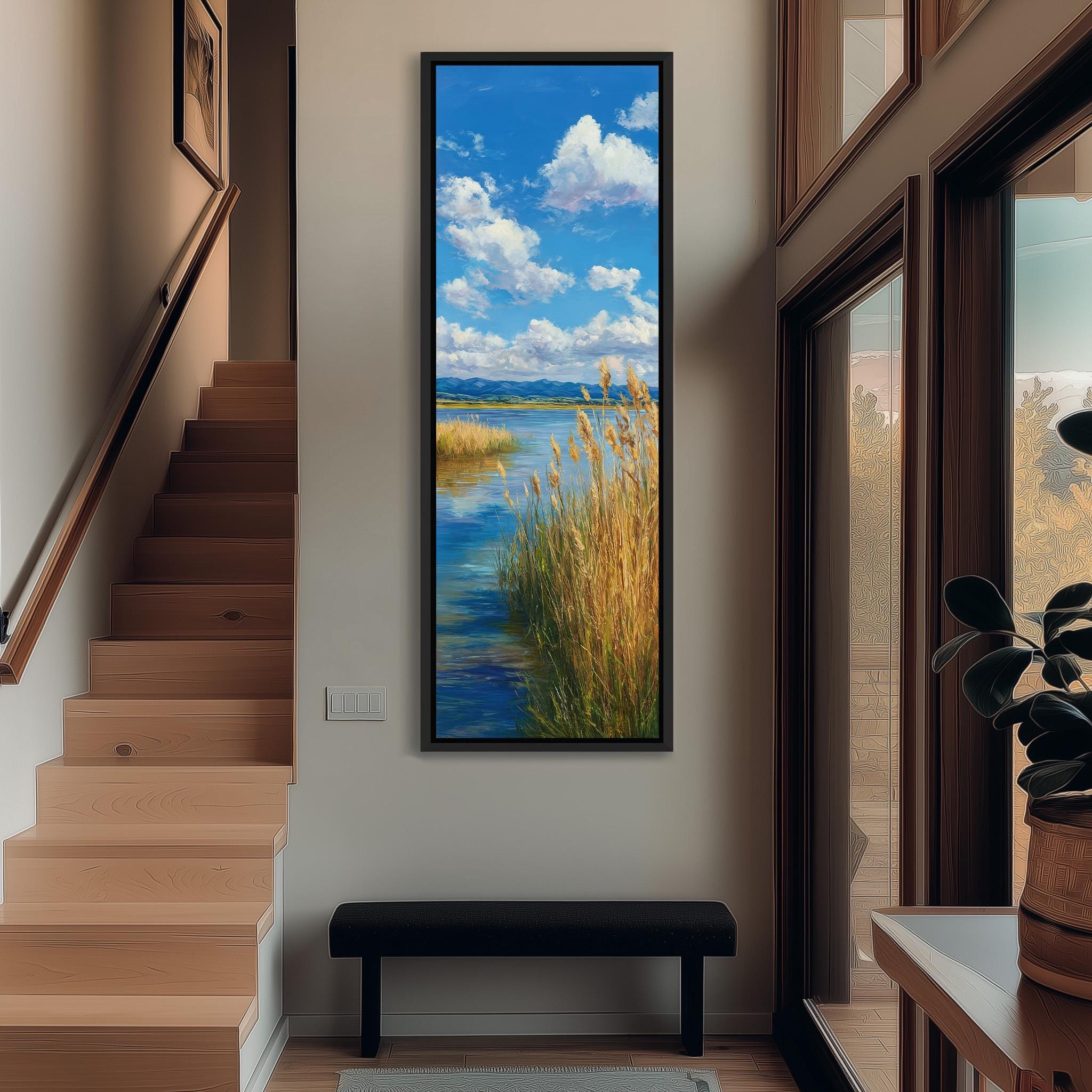 a large painting of a serene landscape hanging on the wall of a hallway. The painting depicts a tranquil scene with a body of water, grassy fields, and a blue sky with fluffy white clouds. The painting is framed and hangs prominently on the wall, adding a touch of nature and beauty to the space.