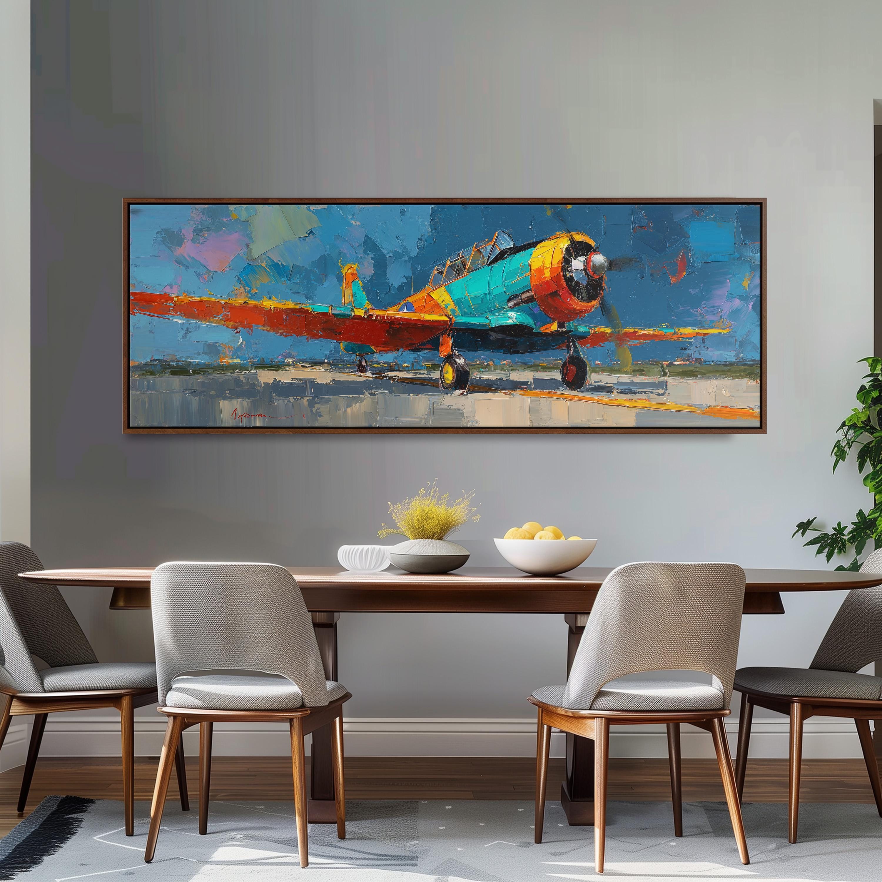 a large painting of a colorful airplane hanging on a wall above a wooden dining table with four chairs.