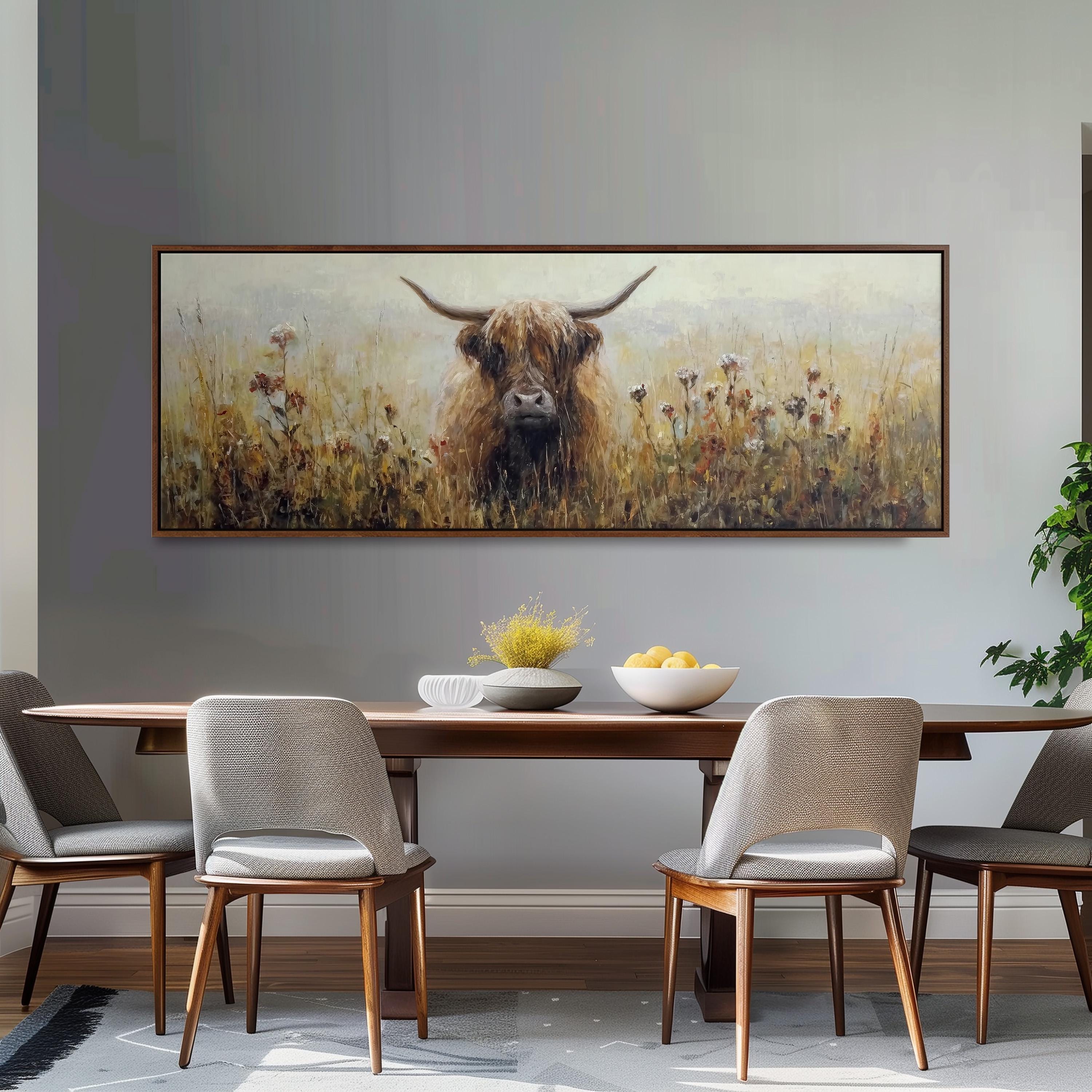 a large painting of a horned animal, likely a yak or a yak dog, in a field with flowers, hanging on a wall above a wooden dining table with four chairs.