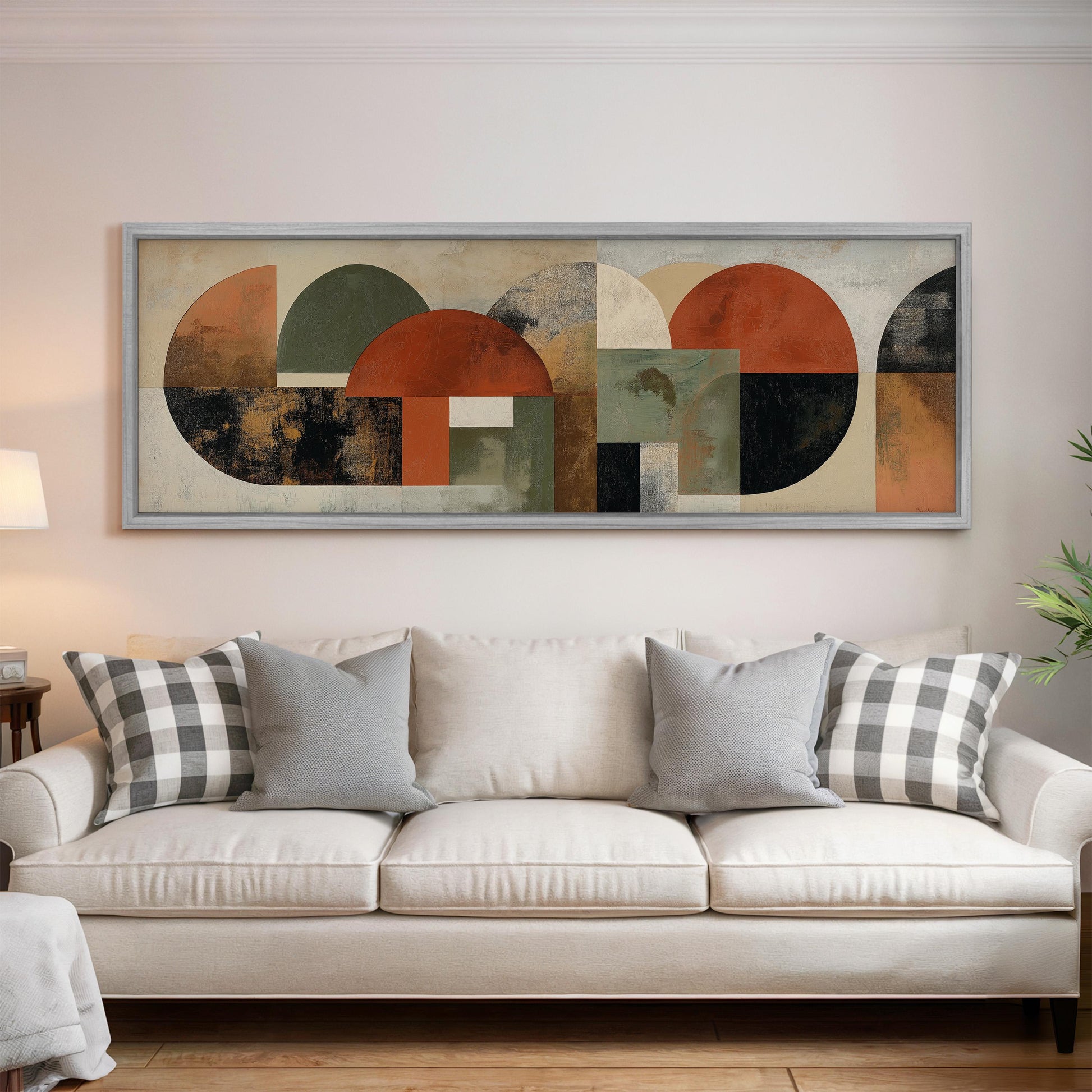 a large abstract painting hanging on a wall above a white couch with gray and black plaid throw pillows.