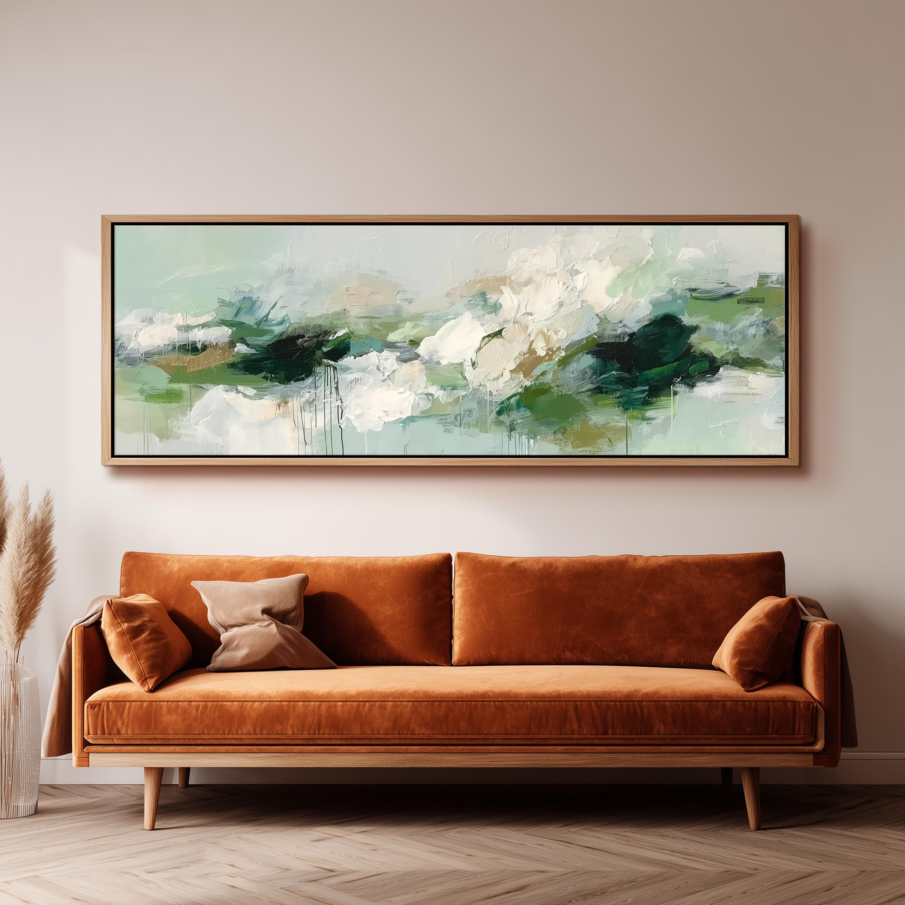 a large, rectangular painting hanging on a wall above a brown sofa with orange cushions.