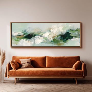 a large, rectangular painting hanging on a wall above a brown sofa with orange cushions.