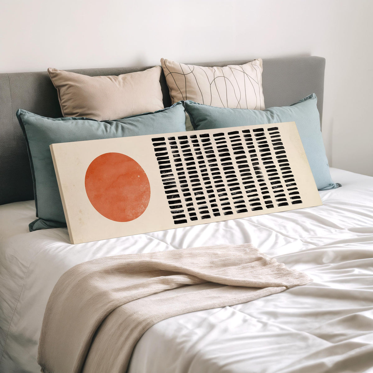 Orange sun beside rows of black dashes wide panoramic canvas print laid on a bed to show its size